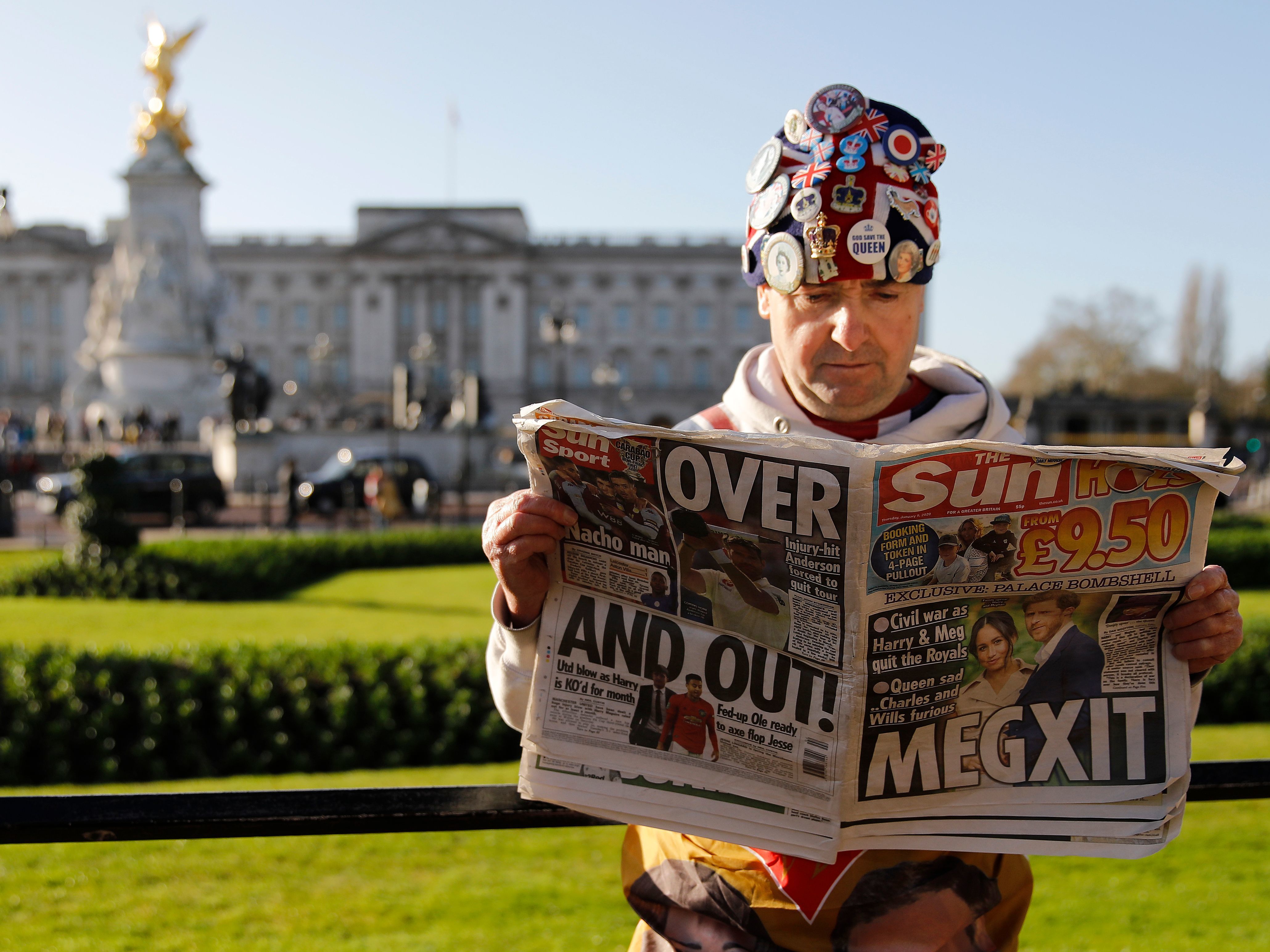 John Loughery, a fan of the royals, reads the day's news outside Buckingham Palace in London on Thursday, following the announcement that Prince Harry and Meghan Markle plan to step down as senior members of the royal family. (AFP via Getty Images)