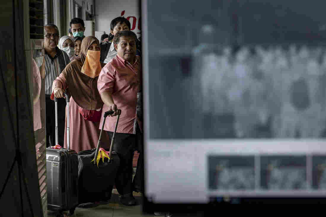 Passengers from an international flight have their temperature checked as they pass a thermal scanner monitor, seen at right, upon arrival at the international Airport in Yogyakarta, Indonesia on Thursday.