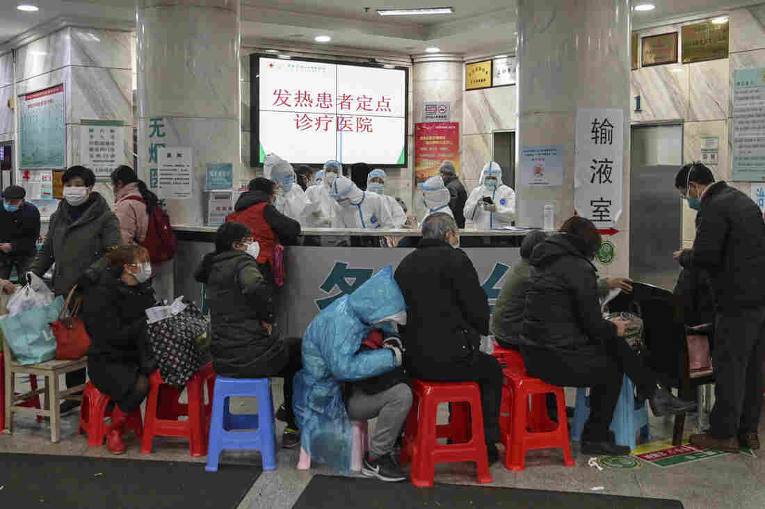 People wait as medical staff wear protective clothing to help stop the spread of a deadly virus which began in the city, at Wuhan Red Cross Hospital in Wuhan on January 24, 2020.