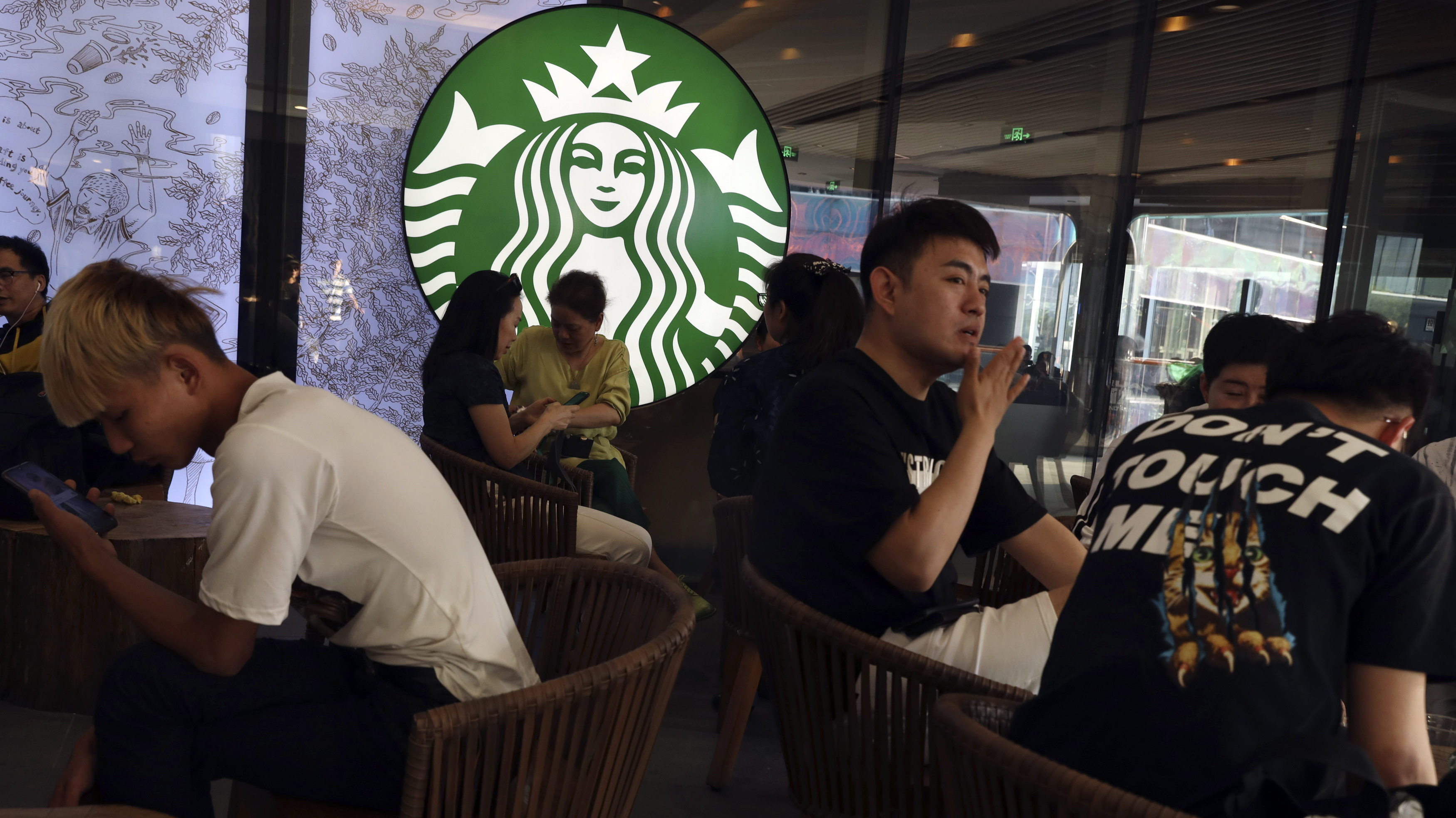 In a photo taken in May, customers enjoy their drinks at a Starbucks in Beijing. The U.S.-based coffee chain as decided to close more than half its stores in mainland China due to the coronavirus outbreak.