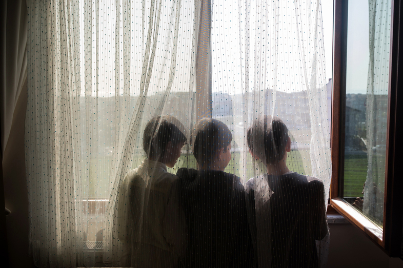Ten-year-old Nurzat (right) and his friends, brothers Abdulla (left), 11, and Muhammet (center), 10, look out the window of their dormitory room at a boarding school in Istanbul, Turkey. The boys are all missing their parents, who are believed to be in prison camps in China. (Nicole Tung for NPR)