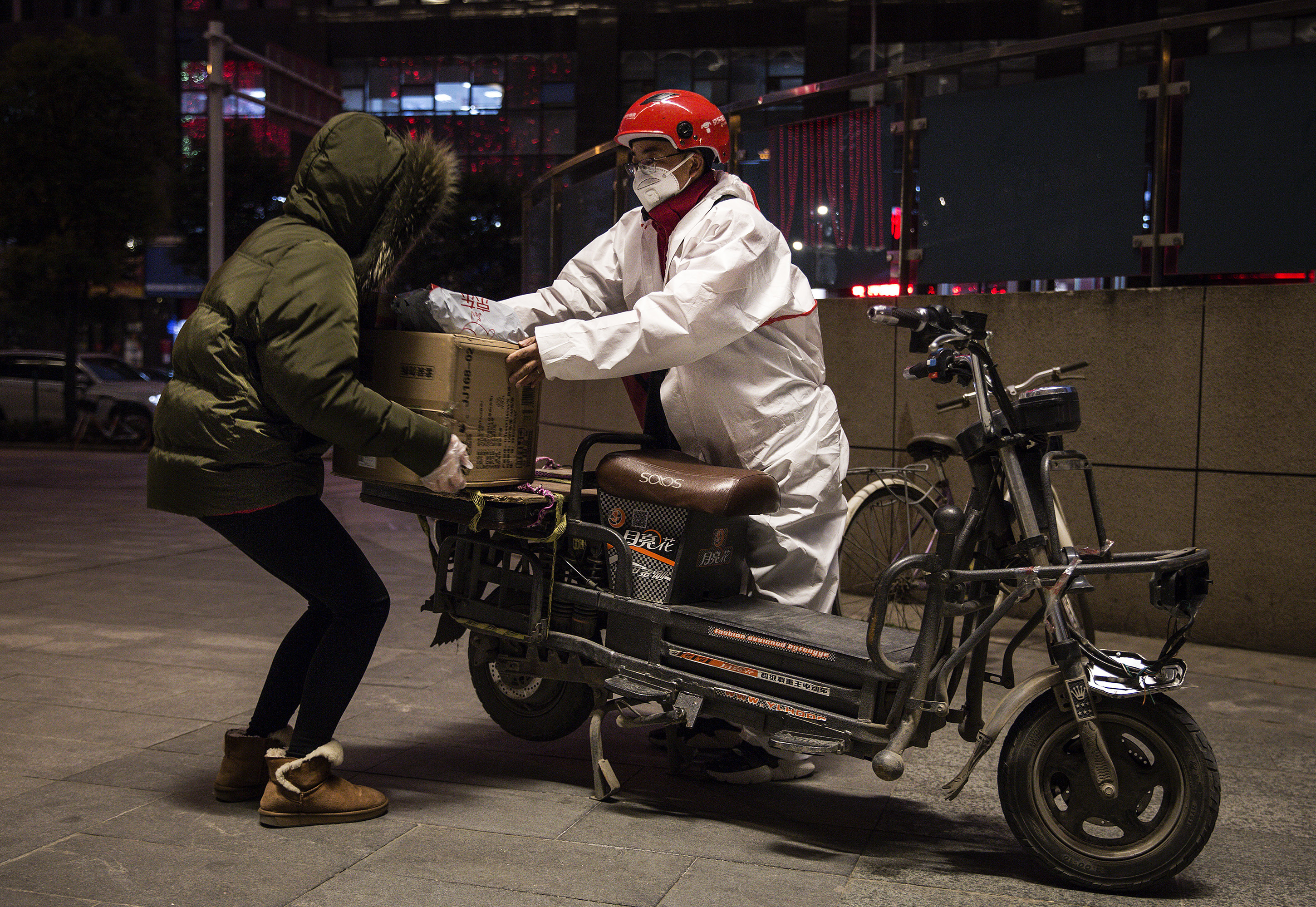 A delivery person wears a protective mask and suit as he delivers packages by bicycle on Saturday in Wuhan, China. (Getty Images)