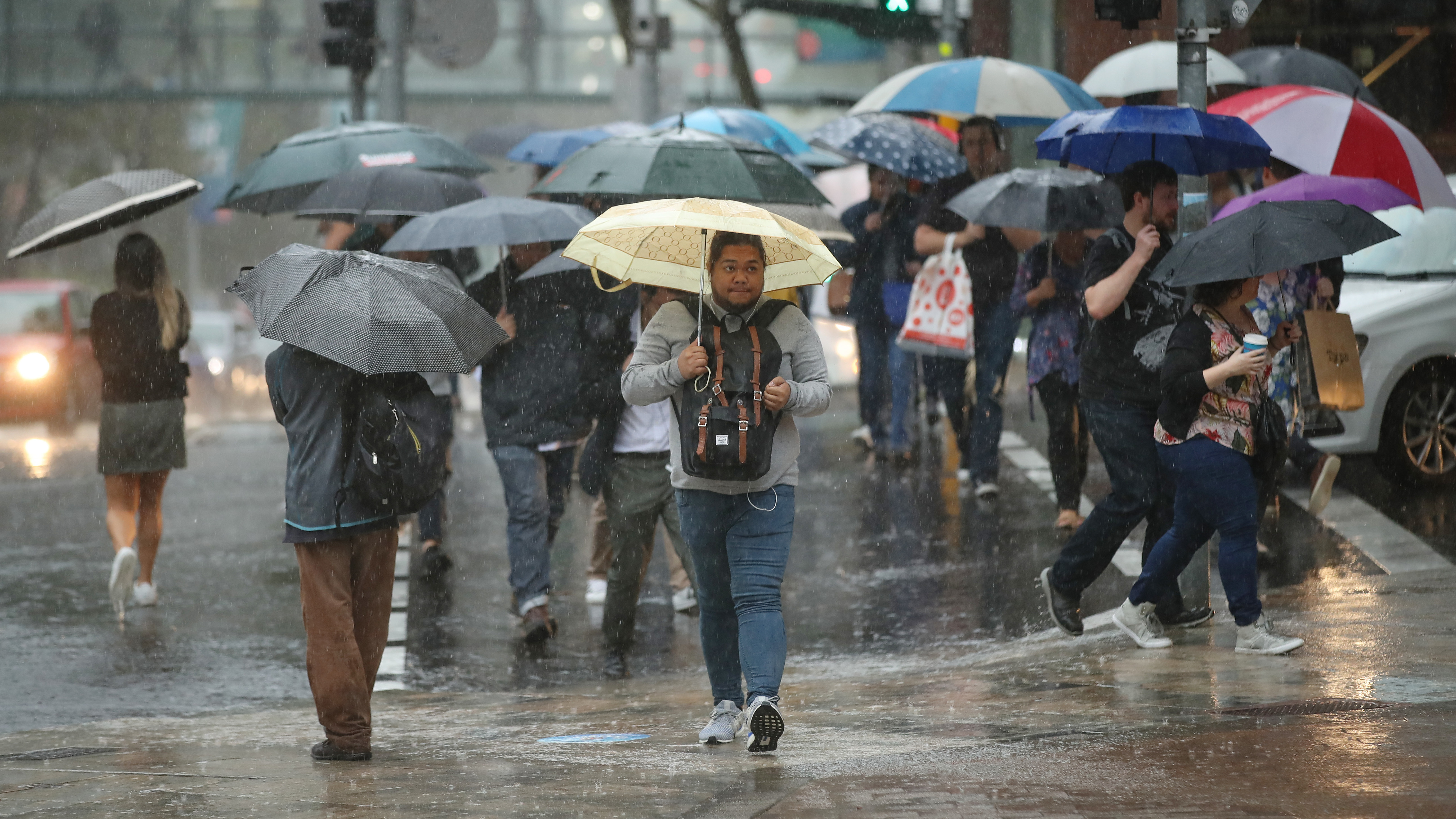 People commute to work through heavy rain in Sydney on Friday. Severe weather brought warnings of floods and landslides along much of the New South Wales coast after months of concerns over wildfires. (Getty Images)
