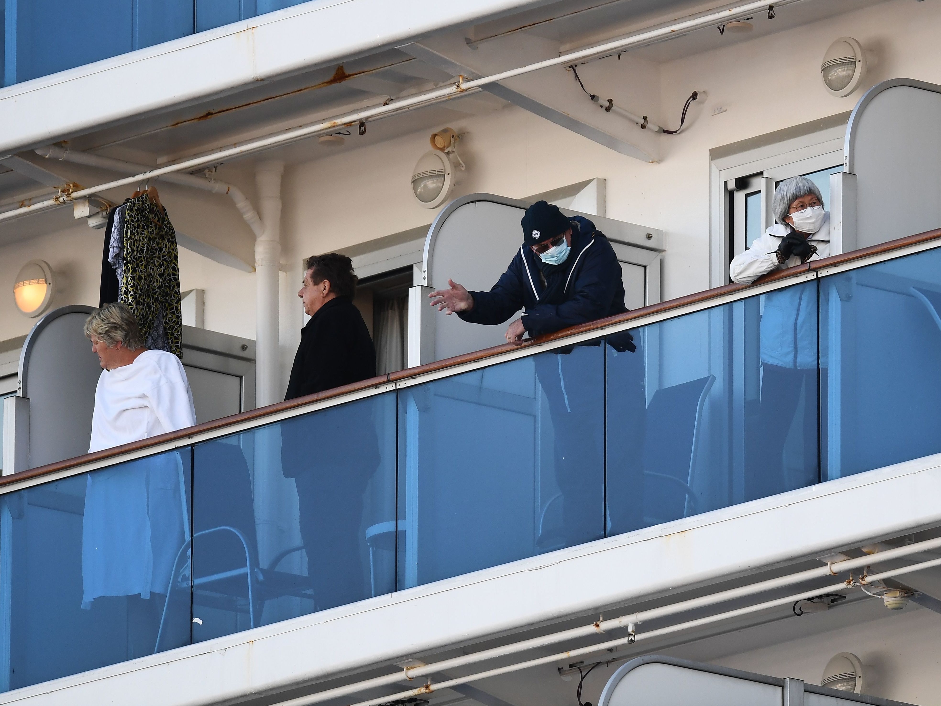 The quarantined Diamond Princess cruise ship has 65 new cases of coronavirus, Japanese officials announced Monday. Here, passengers with ocean-facing rooms stand on their balconies as the ship sits at the Daikoku Pier Cruise Terminal in Yokohama, Japan. (AFP via Getty Images)