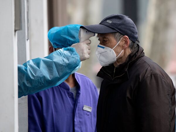 A man wearing a face mask has his temperature checked before entering a community hospital in Shanghai on Thursday. China's official death toll and infection numbers from the deadly COVID-19 coronavirus spiked dramatically on Thursday after authorities changed their counting methods.