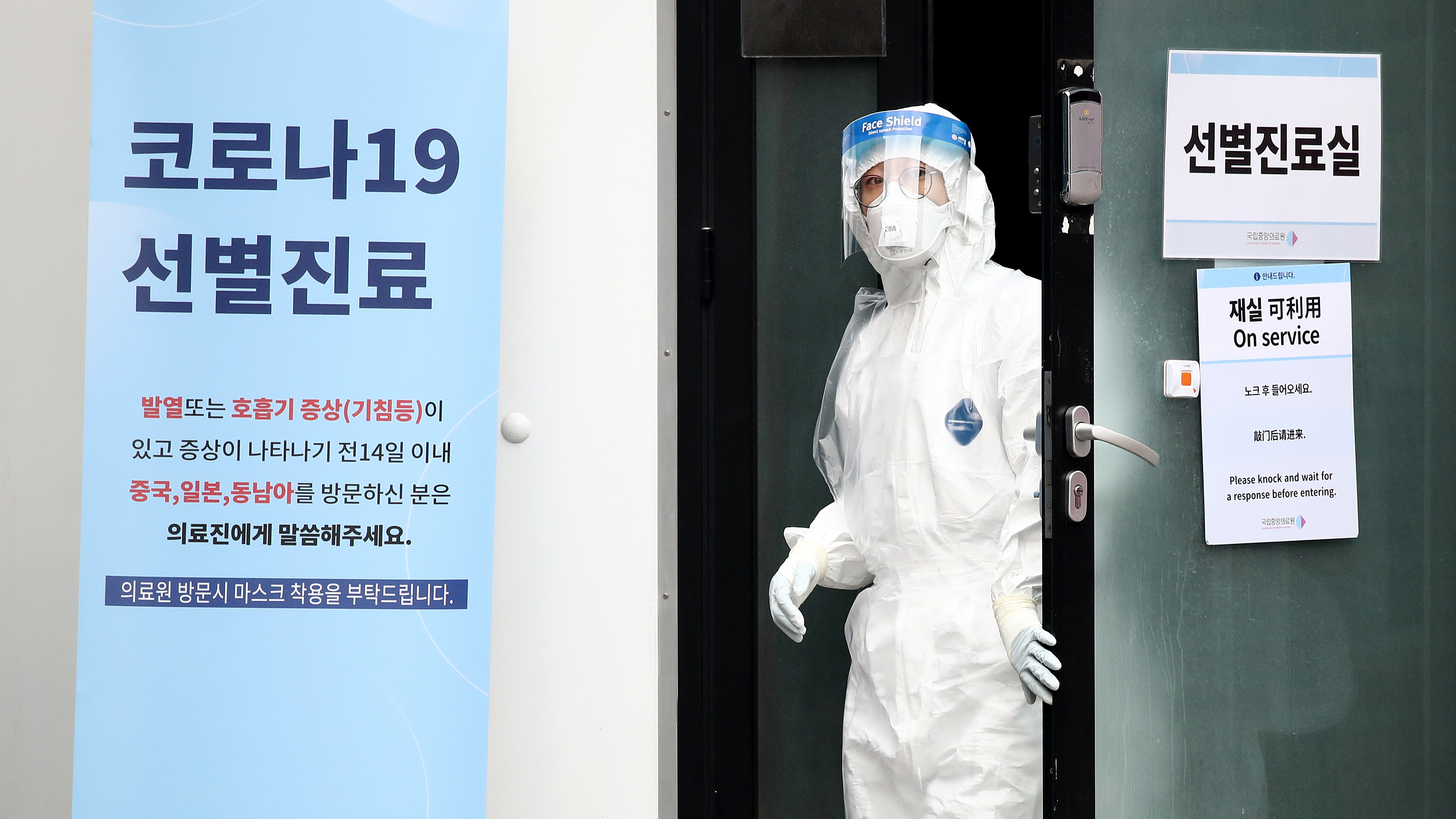 A medical worker takes a look outside a preliminary testing facility at the National Medical Center in Seoul, South Korea, where people suspected of having contracted the novel strain of coronavirus are being tested. (Getty Images)