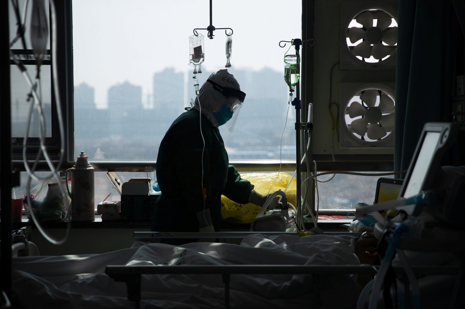 A medical worker in a protective suit tends to a patient in a hospital in Wuhan, China. (China Daily CDIC/Reuters)