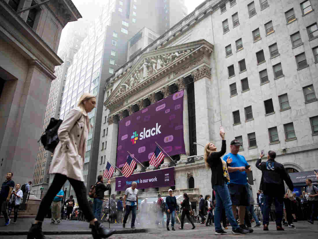 Pedestrians pass in front of a Slack Technologies Inc. signage displayed outside of the New York Stock Exchange Photographer: Michael Nagle/Bloomberg via Getty Images