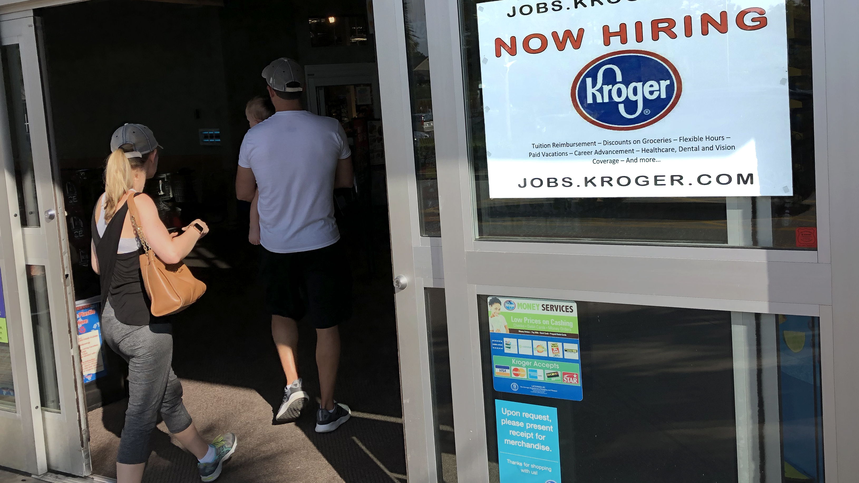 A hiring sign hangs in front of a Kroger