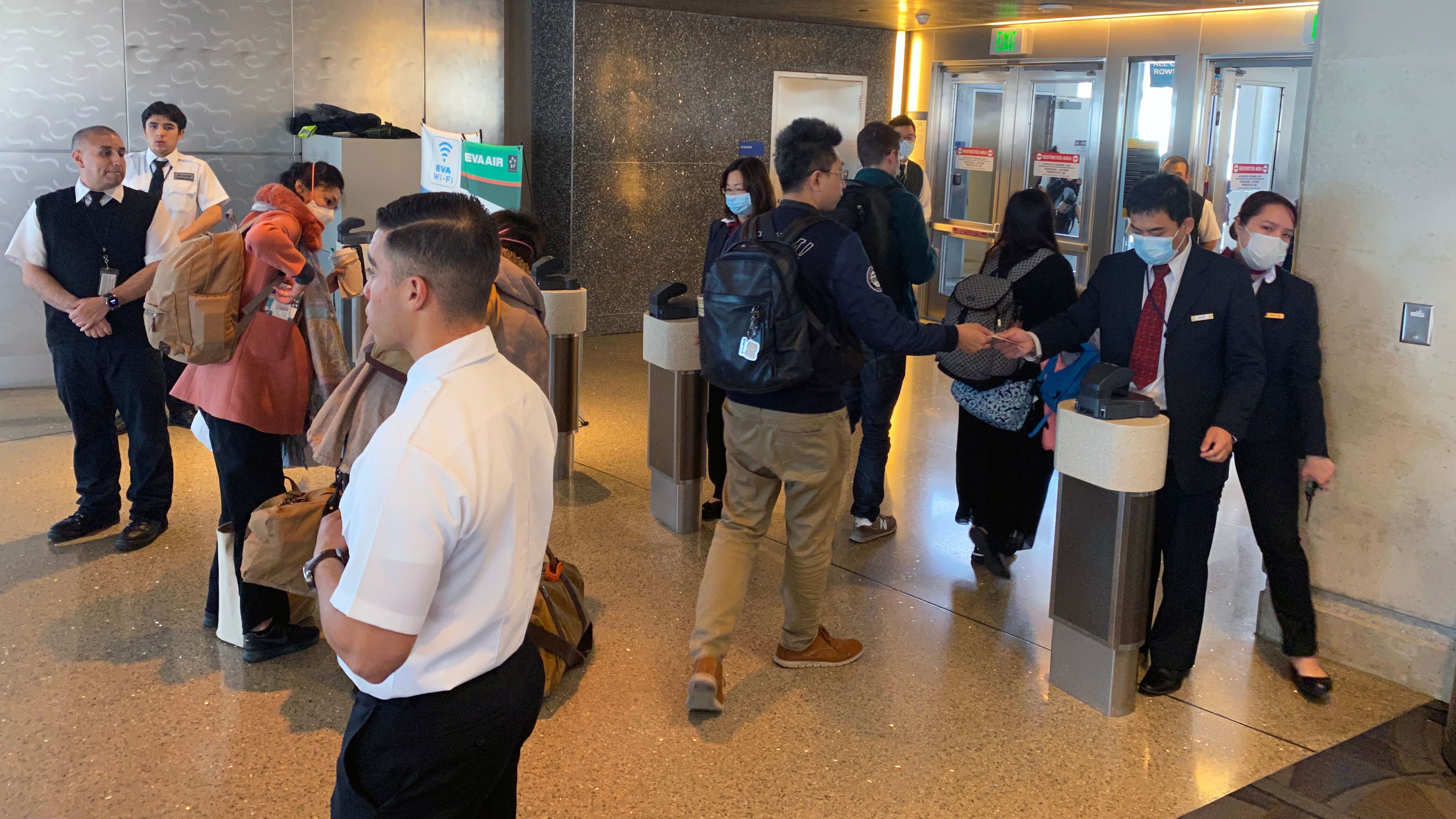 Humans — workers and flight crews as well as passengers — can be exposed to any number of pathogens at airports. EVA Air employees are seen wearing face masks at the Los Angeles airport in February amid the coronavirus outbreak. U.S. officials advise masks are not the best way to mitigate one