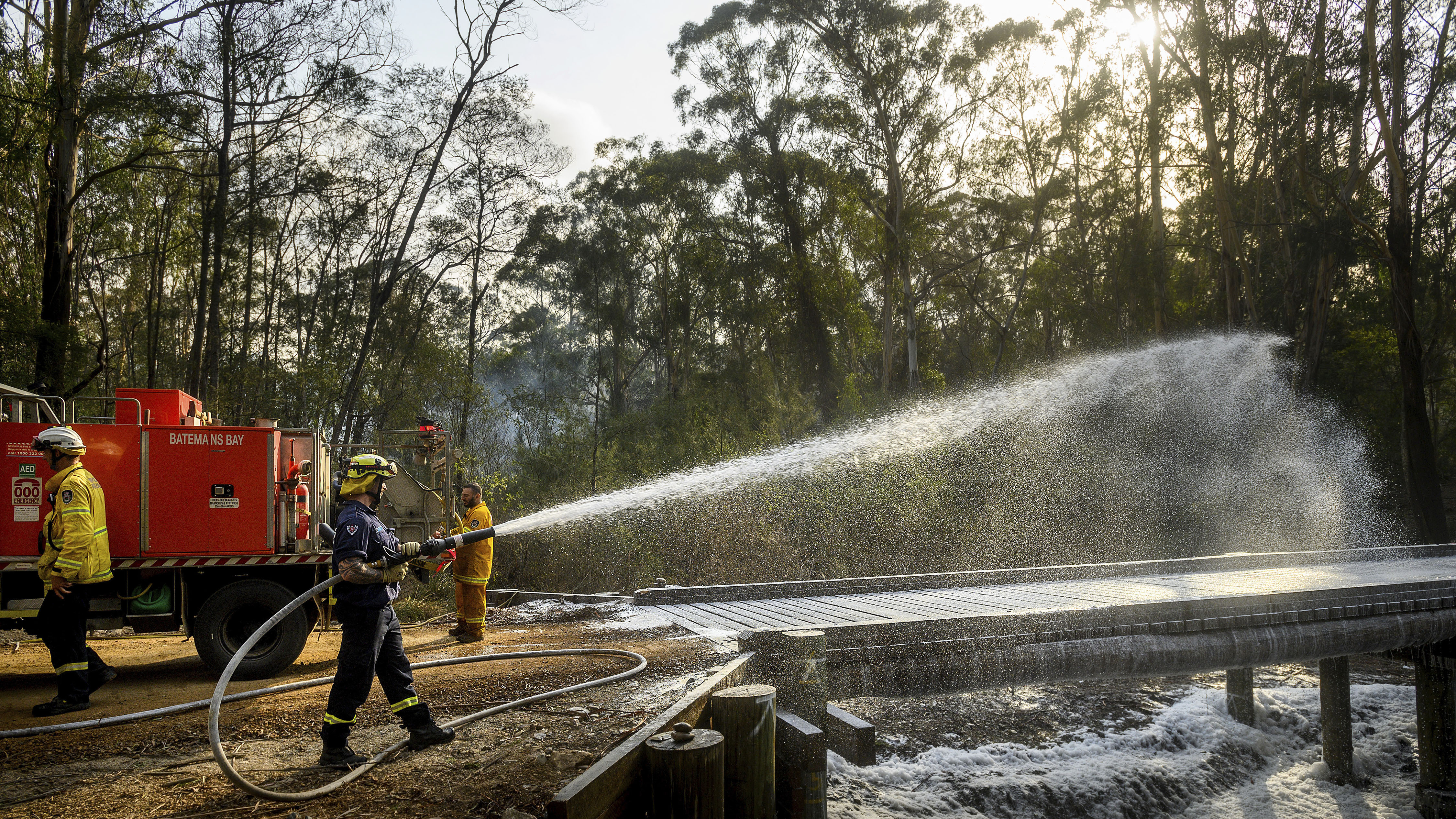 A firefighter coats a bridge with foam as a bushfire burns near Moruya, New South Wales, Australia, on Jan. 25. Wildfires destroyed more than 3,000 homes and razed more nearly 11 million hectares since the summer fires began.