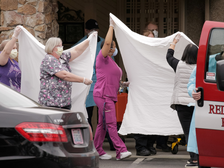 Health care workers transfer a patient to an ambulance at the Life Care Center of Kirkland, Wash., the long-term care facility where the two people who had posthumous diagnoses of COVID-19 were residents. (David Ryder/Reuters)