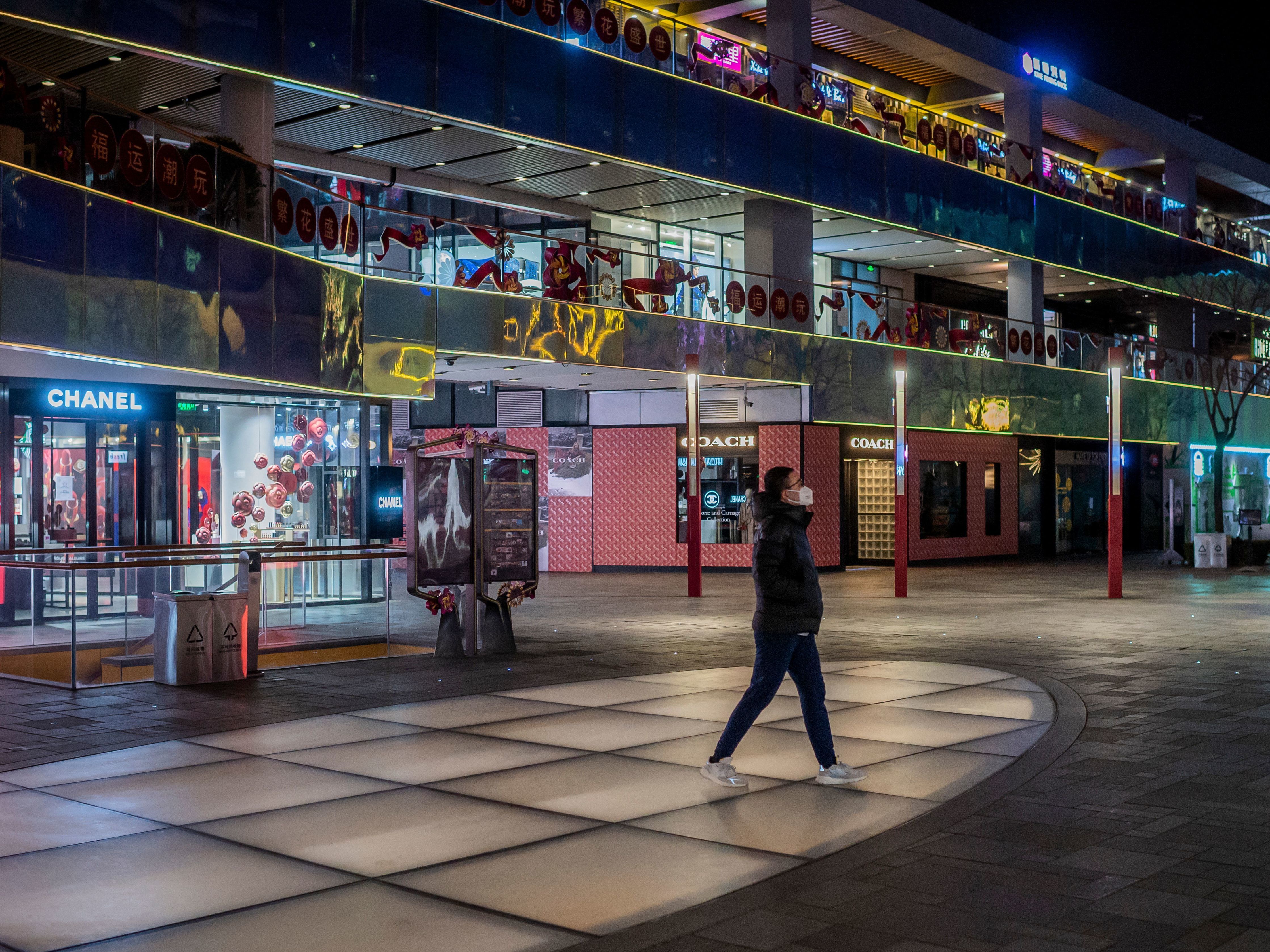 A man wearing a protective face mask walks at a nearly empty shopping mall in Beijing on Feb. 27. Business activity in China has all but halted, with entire cities under quarantine and industries forced to lay off workers. (AFP via Getty Images)