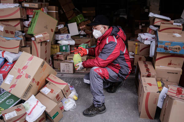 A courier uses alcohol to disinfect packages in order to prevent any potential coronavirus pathogens from spreading to themselves and customers.