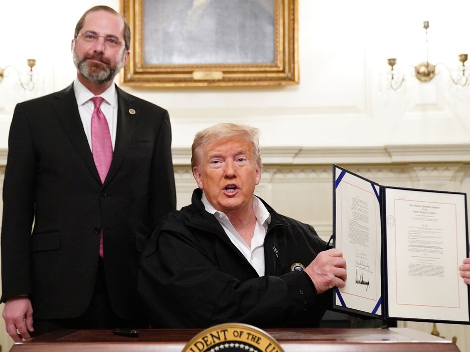 President Trump holds up the $8 billion coronavirus emergency funding bill after signing it at the White House as Health Secretary Alex Azar looks on. (Mandel Ngan/AFP via Getty Images)