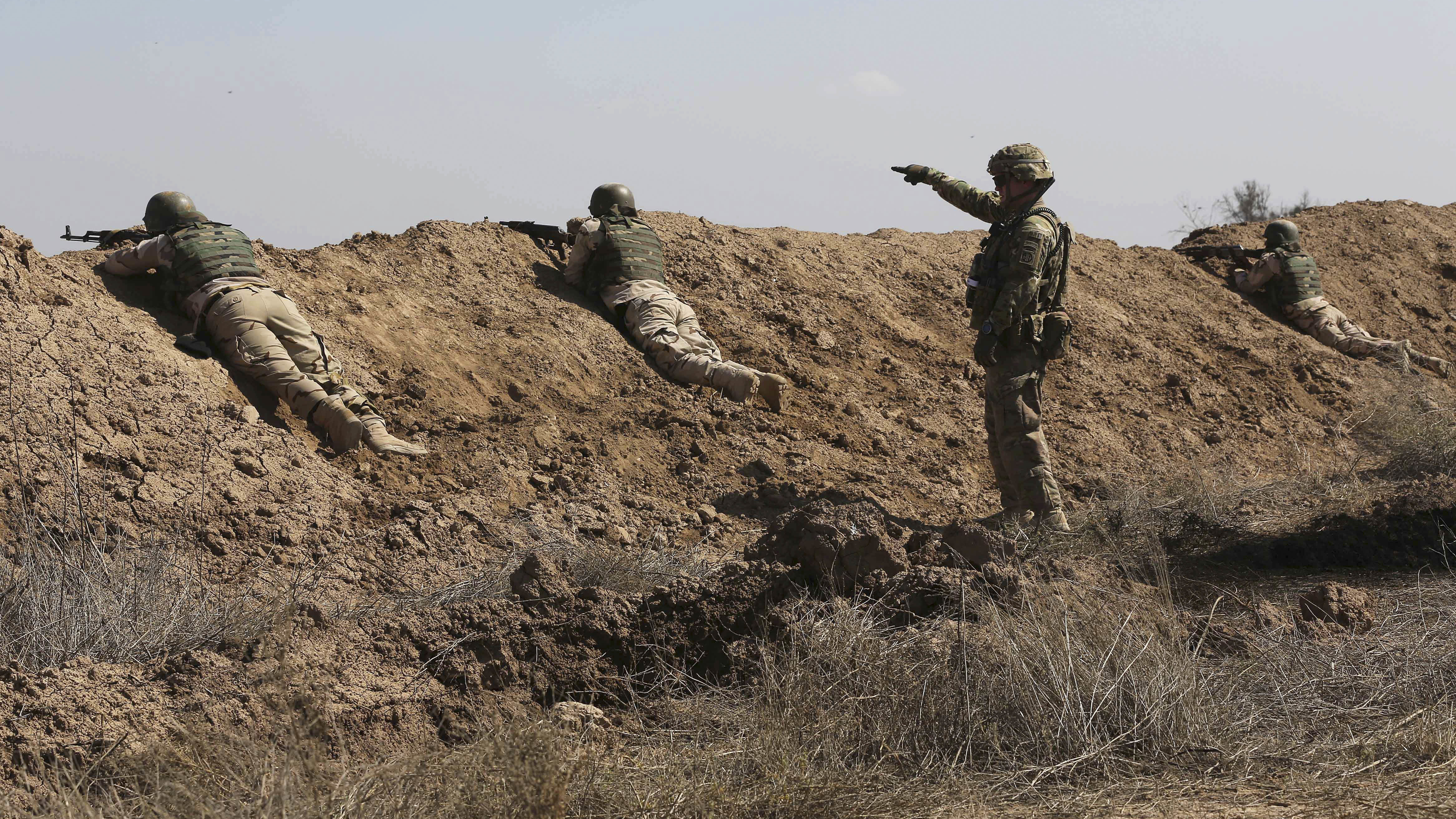 A U.S. soldier (standing) helps Iraqi security forces improve shooting skills at Camp Taji, north of Baghdad, in 2015.
