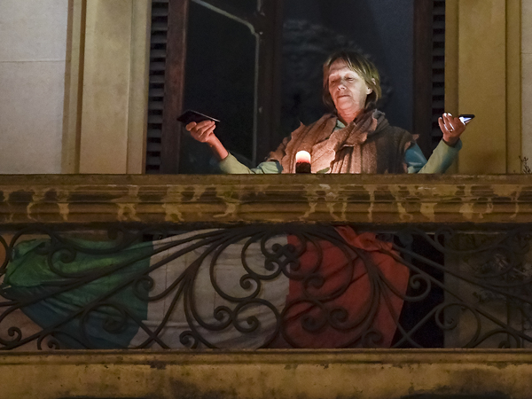 A woman holds lights on her balcony during a flash mob launched throughout Italy on March 15 to bring people together. The Italian government imposed unprecedented restrictions to halt the spread of COVID-19 coronavirus outbreak, among other measures people are allowed only to leave home for work, for buying essential goods and for health reasons.