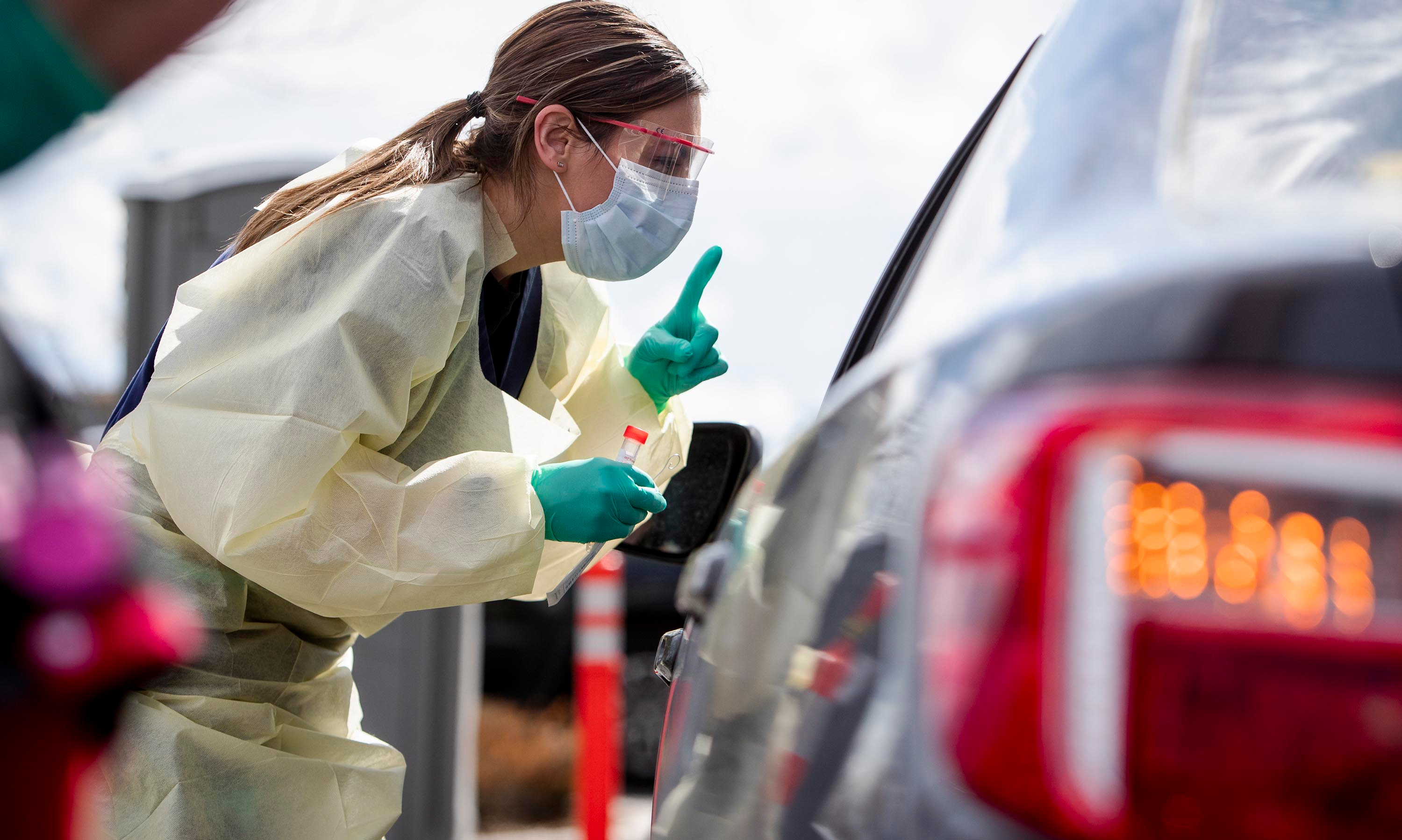 Drive-through screening stations are opening up in several parts of the country as testing capacity starts to expand nationally. At one station in Meridian, Idaho, nurse Ashley Layton communicates with a patient before taking a swab sample. (Idaho Statesman/Tribune News Service via Getty Images)