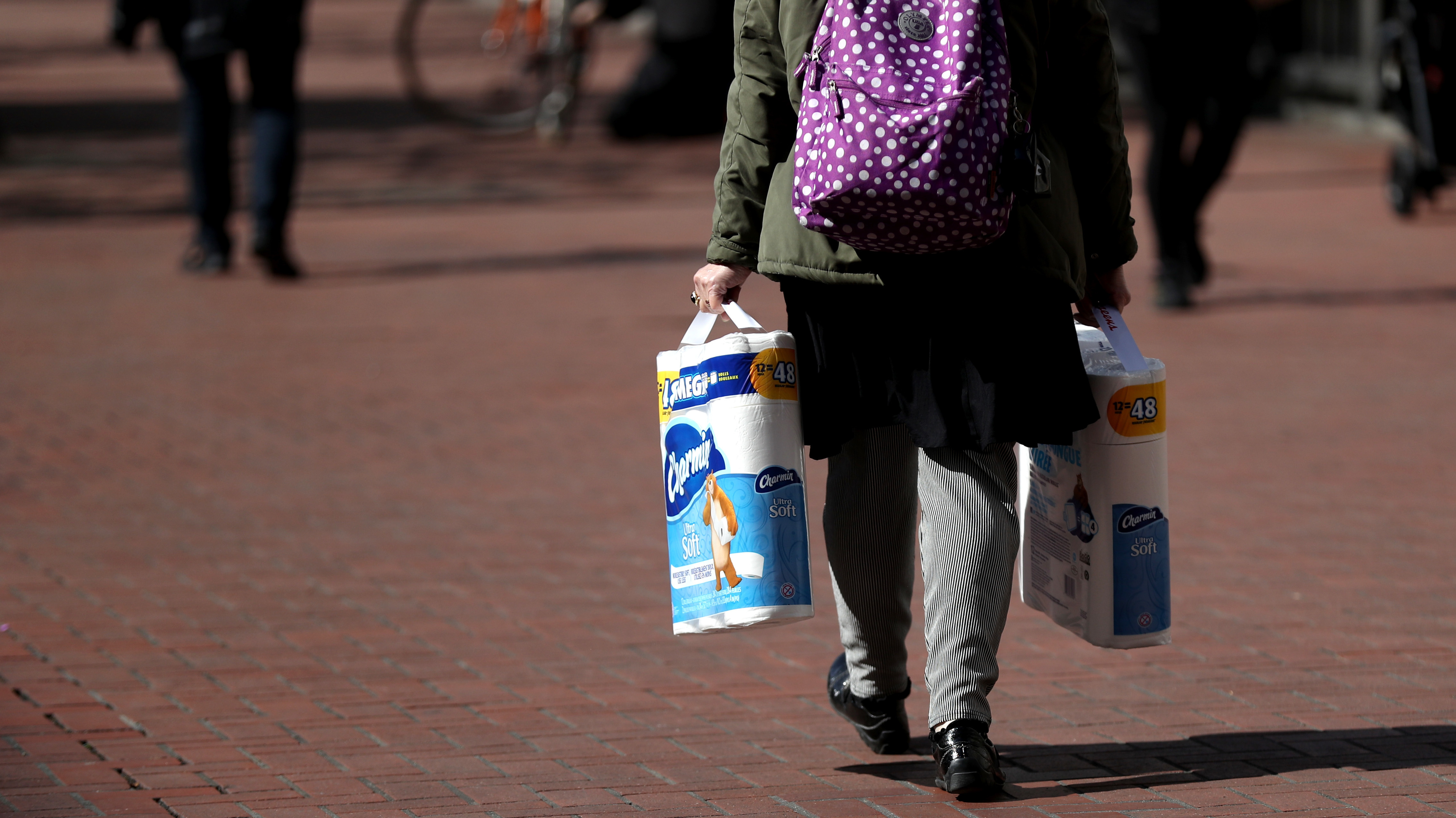 A pedestrian carries two packages of toilet paper as she walks along Market Street in San Francisco earlier this month. (Getty Images)