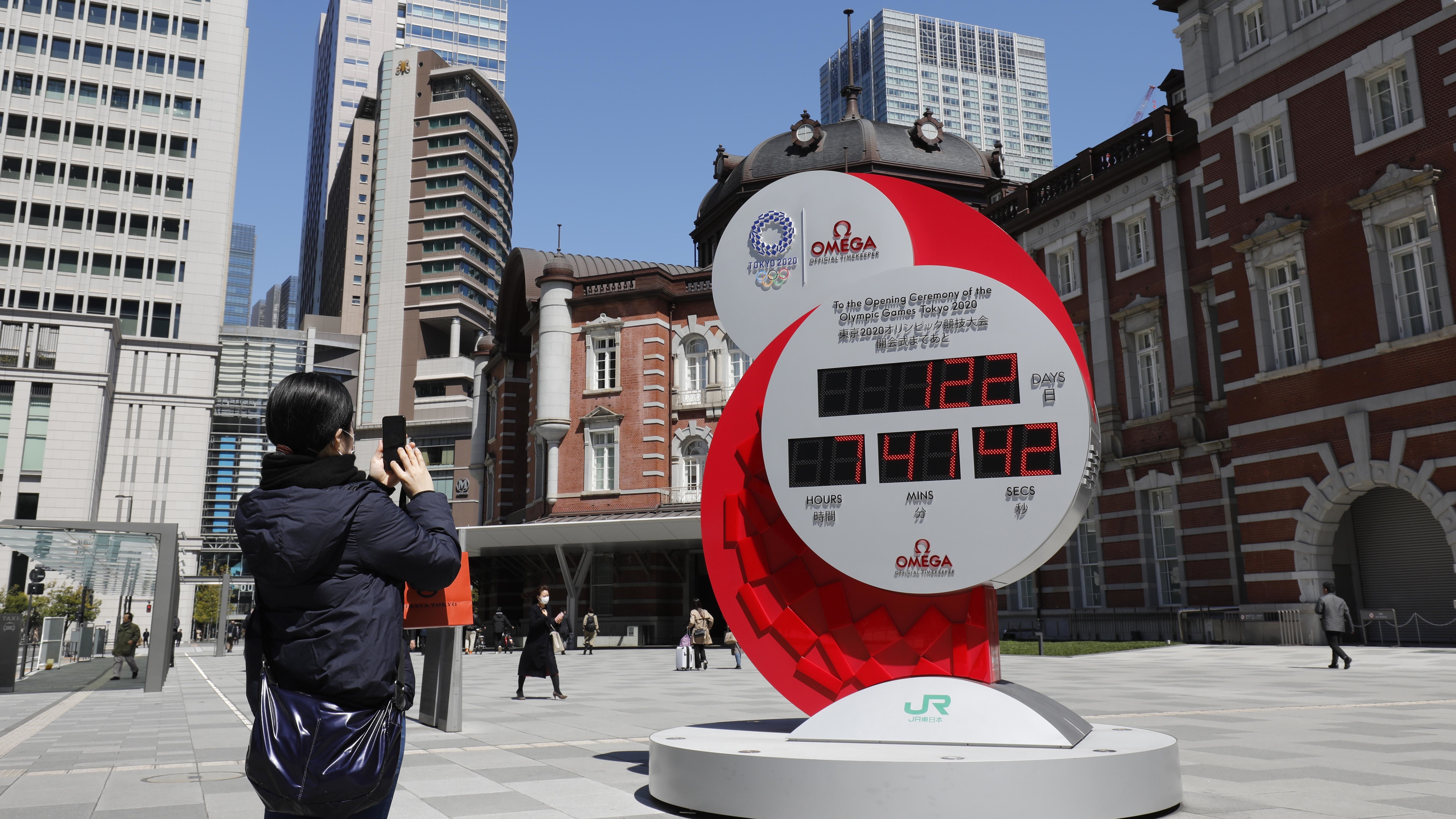 A person in Tokyo takes a photo of a clock counting down the days until the planned start of the Tokyo Games. They will now take place next year. (USA Today Sports via Reuters)