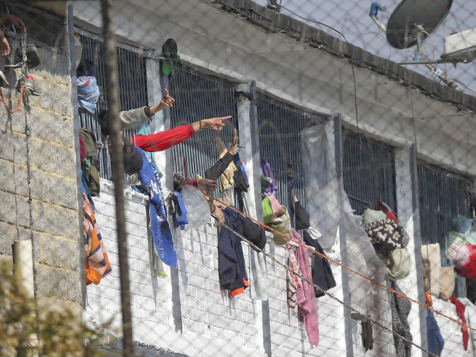 Inmates point from inside the La Modelo facility in Bogotá, Colombia, on Sunday. Violence broke out in the prison out of inmates' fears that prison guards are not doing enough to prevent coronavirus inside overcrowded prisons. (Ivan Valencia/AP)