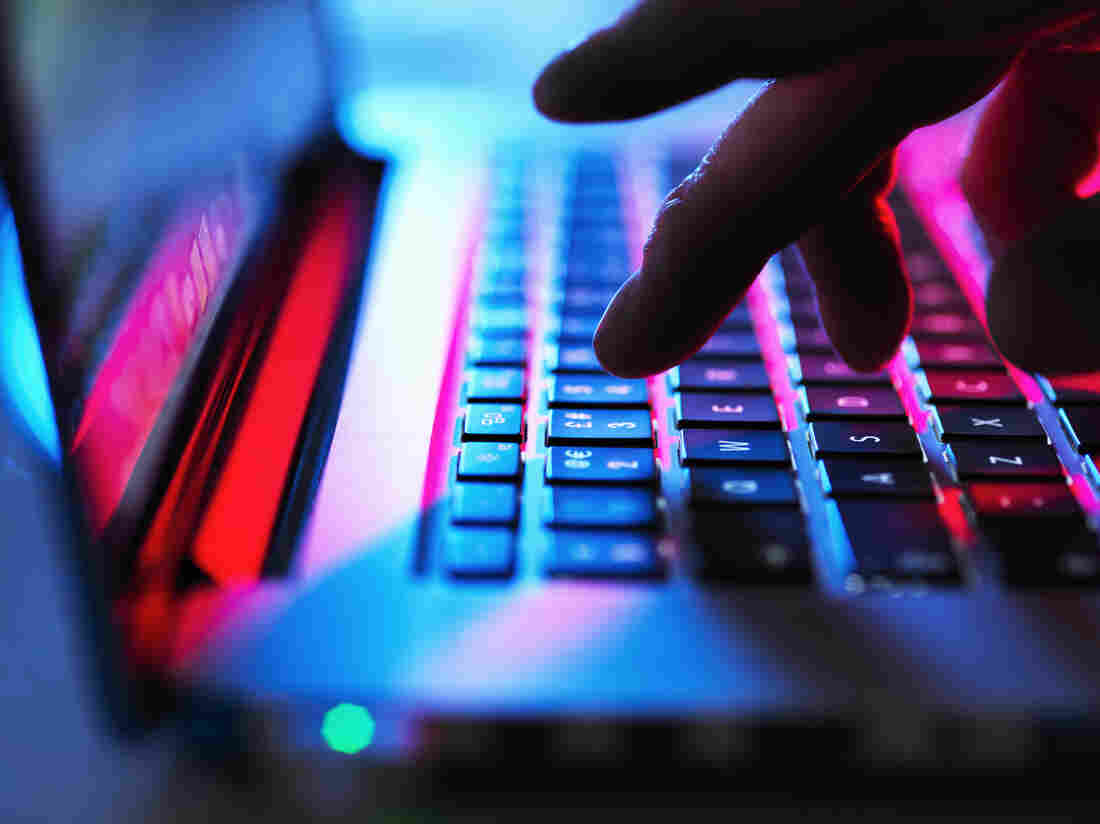 A hand hovers over a computer keyboard.