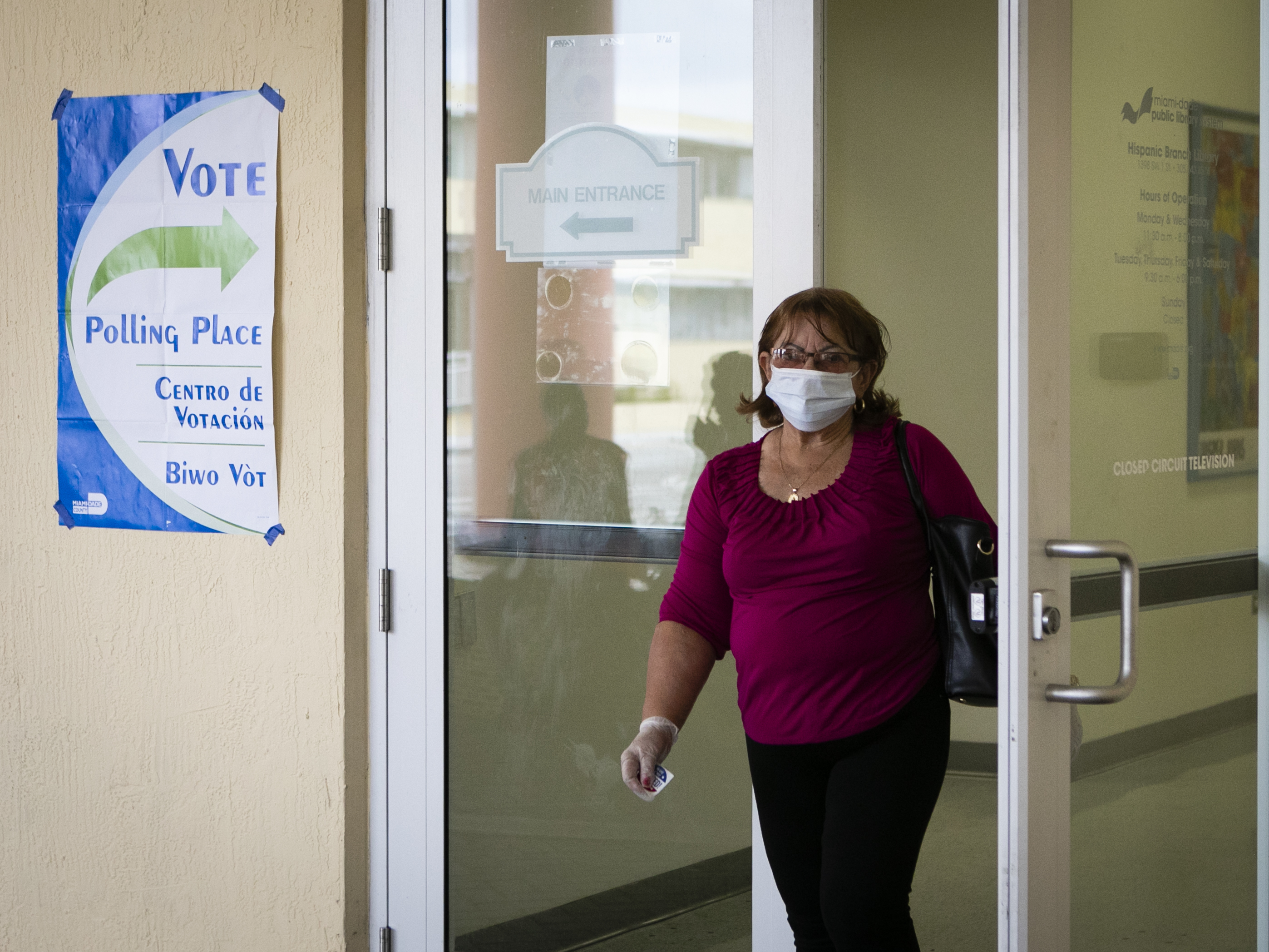 A woman wearing a mask and protective gloves leaves after casting her vote in the Florida Democratic primary election in Miami on March 17. (AFP via Getty Images)