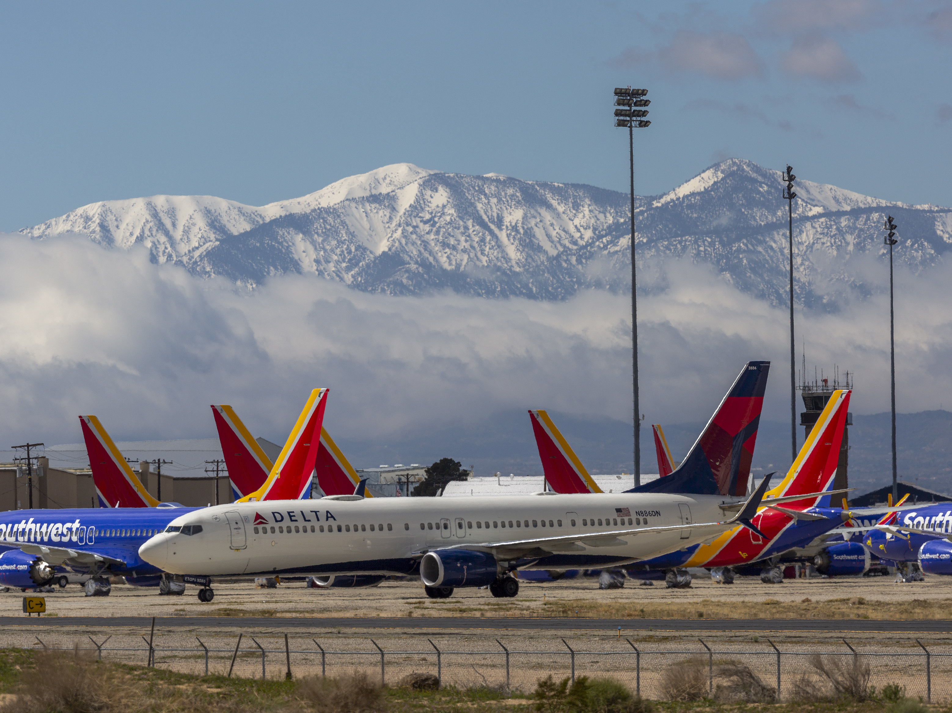 A Delta Air Lines jet taxis past Southwest Airlines jets to be parked with a growing number of jets at Southern California Logistics Airport on Tuesday in Victorville, Calif. Airlines around the world are scrambling to find places to park planes. (Getty Images)
