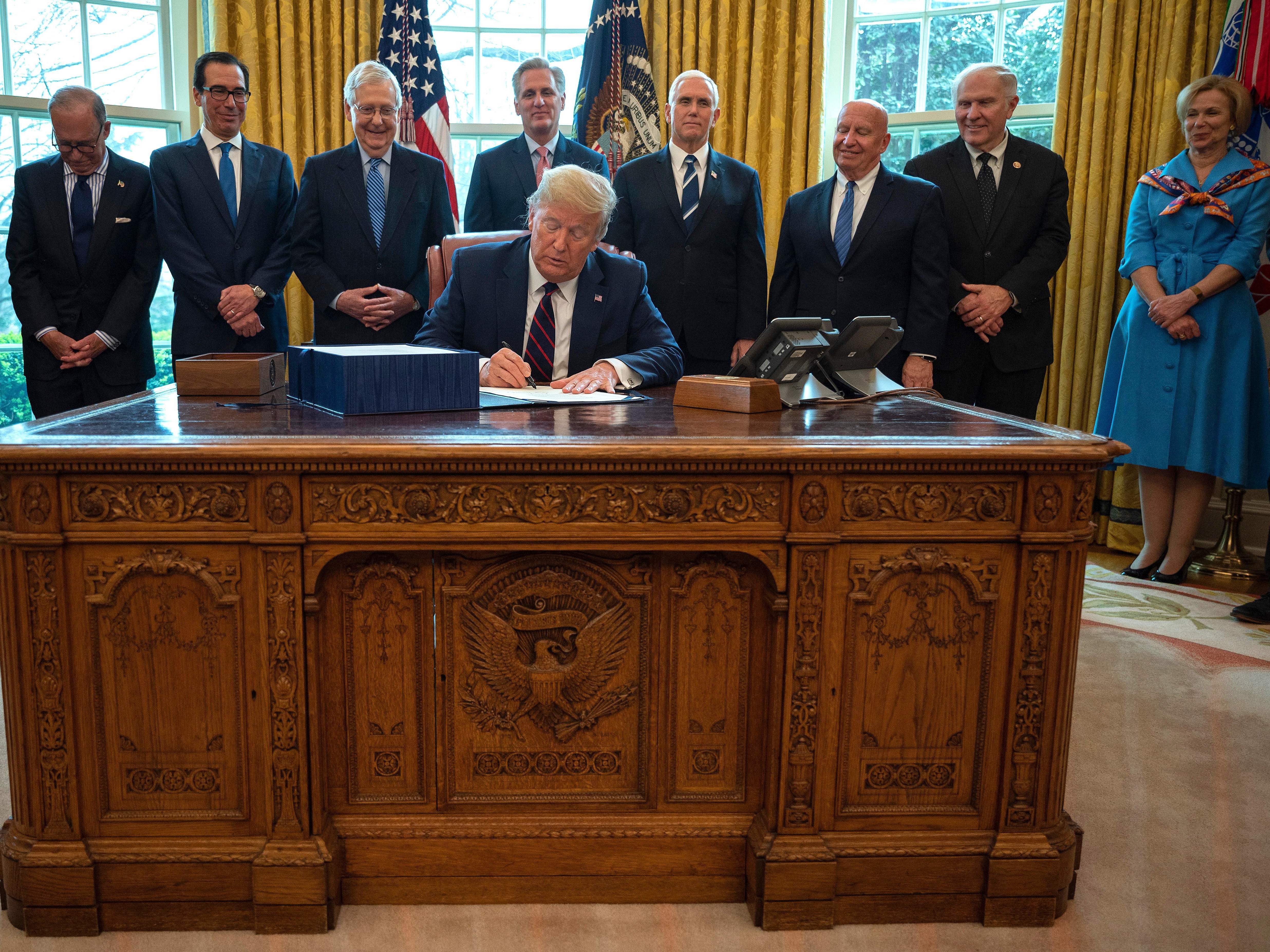 President Trump signs the CARES act, a $2 trillion rescue package to provide economic relief amid the coronavirus outbreak, at the Oval Office of the White House on Friday. (AFP via Getty Images)