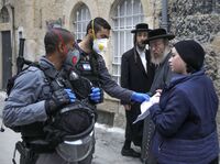 Israeli police officers wearing protective gloves and masks check papers as they enforce restrictions in an ultra-Orthodox Jewish neighborhood in Jerusalem on Tuesday, during a partial lockdown to curb spread of coronavirus infection.