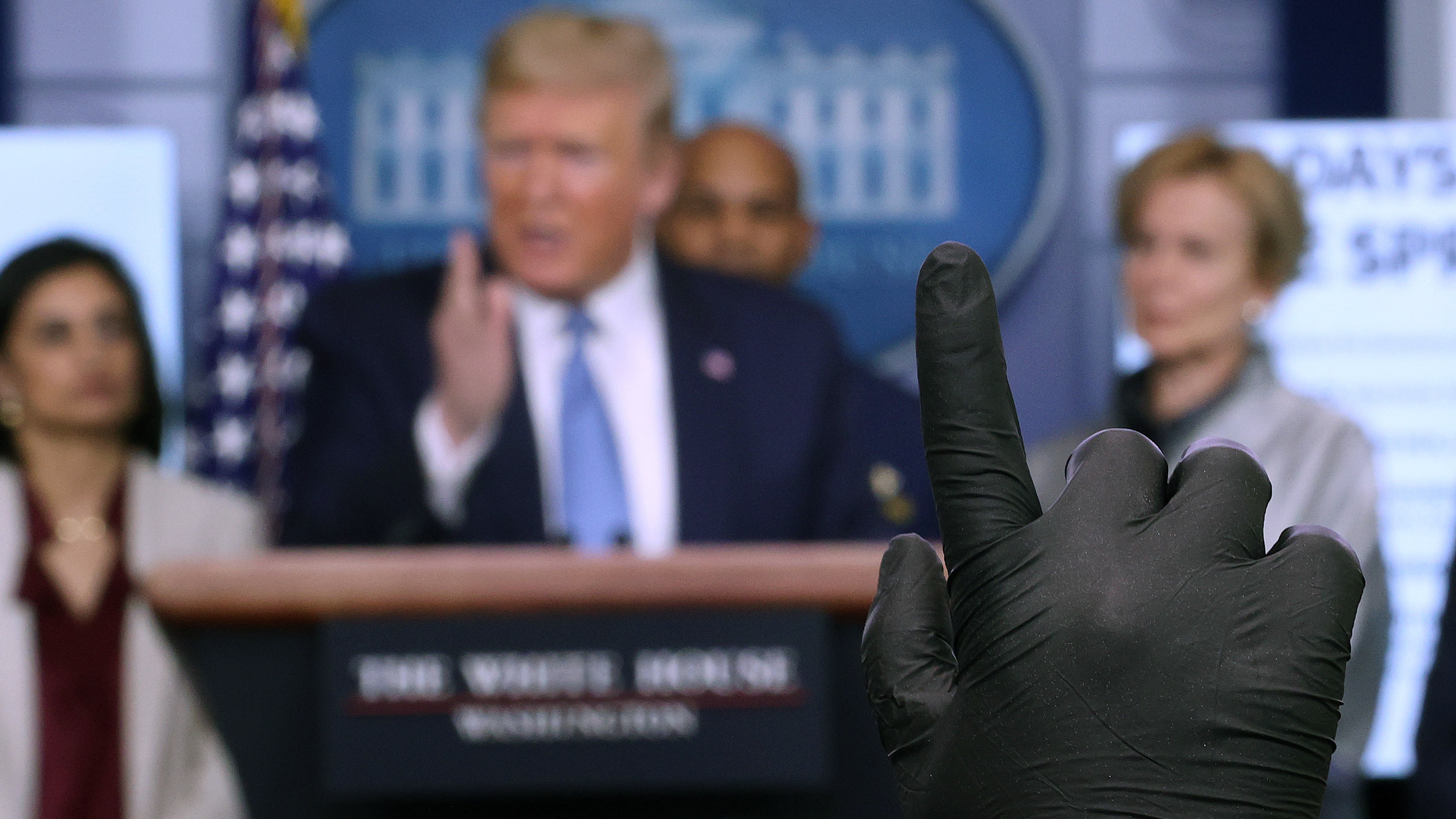 A reporter wearing a latex glove raises his hand to ask President Trump a question during a coronavirus briefing at the White House on March 16.