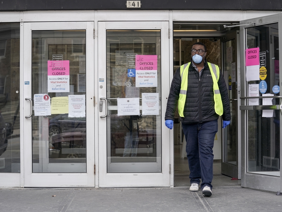 A worker leaves the the Frank P. Zeidler Municipal Building in Milwaukee late last month. Gov. Tony Evers has suspended in-person voting in the state's primary, which was scheduled for Tuesday April 7. (Morry Gash/AP)