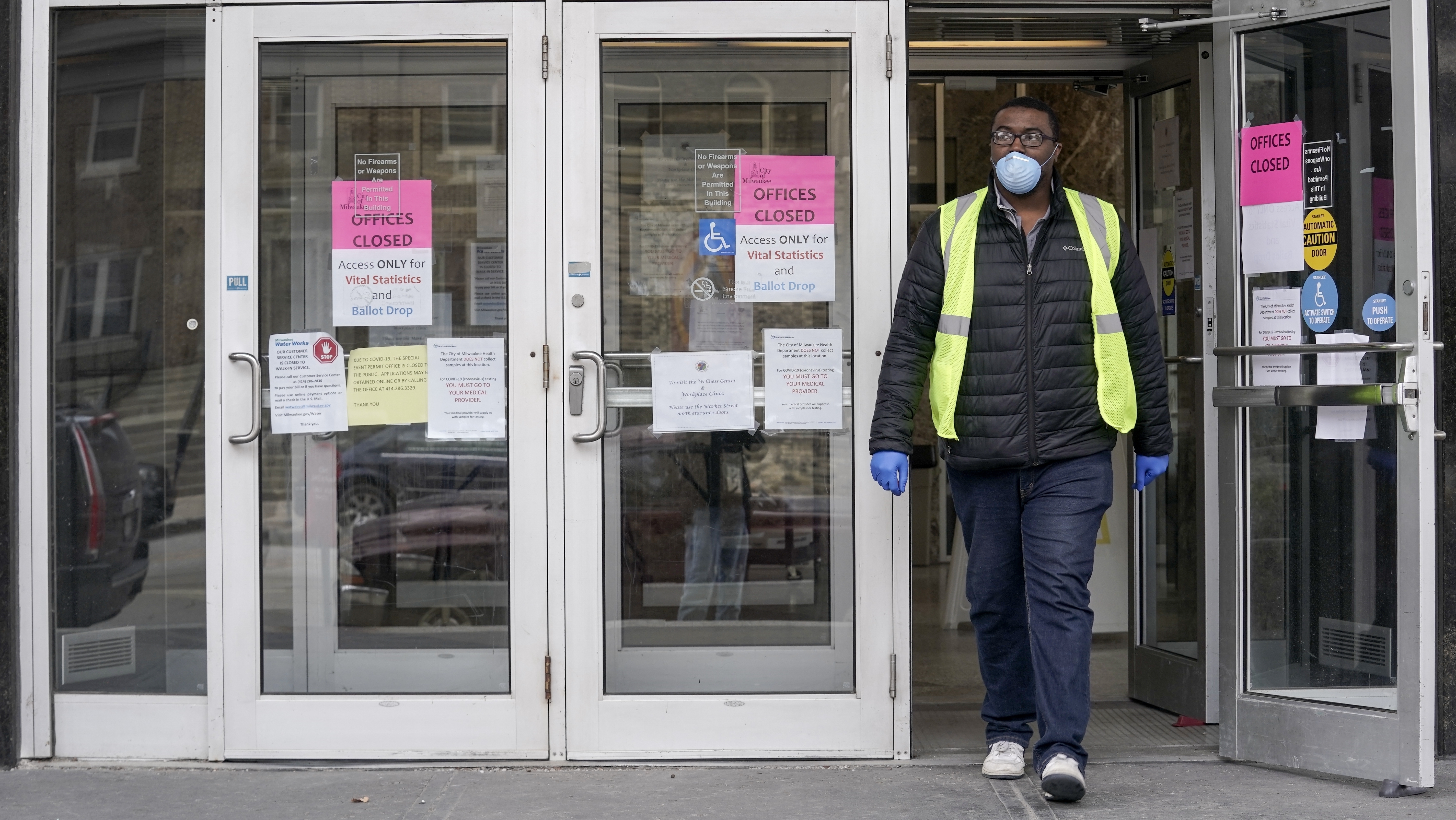 A worker leaves the the Frank P. Zeidler Municipal Building in Milwaukee late last month. Gov. Tony Evers has suspended in-person voting in the state