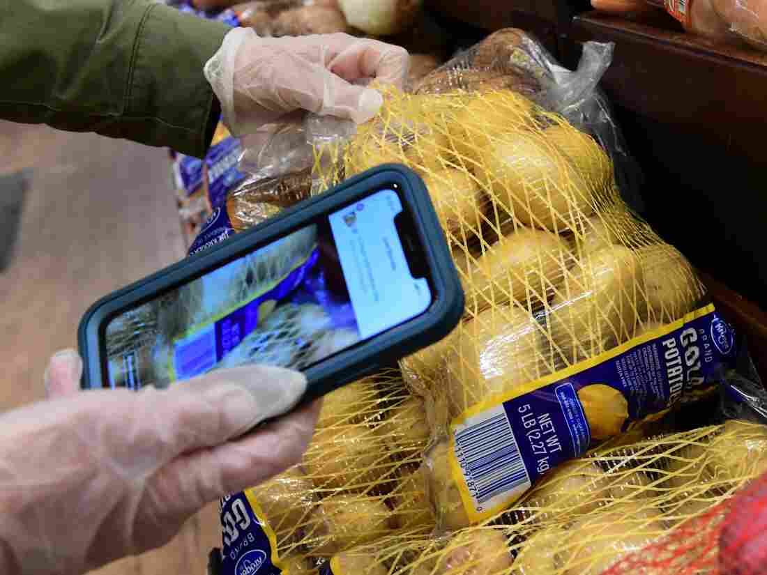 Instacart employee Monica Ortega uses her cellphone to scan barcodes showing proof of purchase for the customer while picking up groceries (Photo by FREDERIC J. BROWN/AFP via Getty Images)