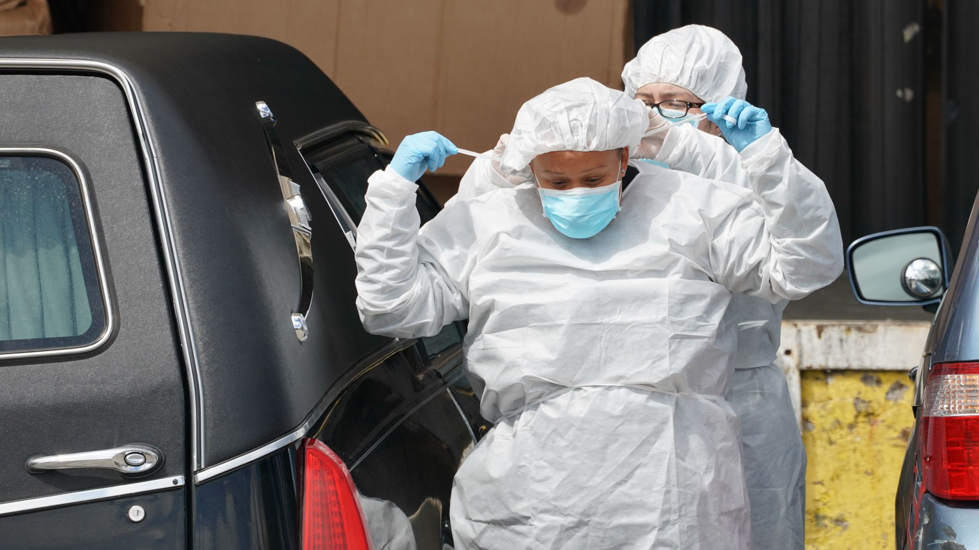 Funeral home workers put on protective gear to retrieve a body from a refrigerated truck outside of a Brooklyn hospital in early April. As of Sunday, the U.S. reported the most coronavirus deaths in the world, surpassing Italy.