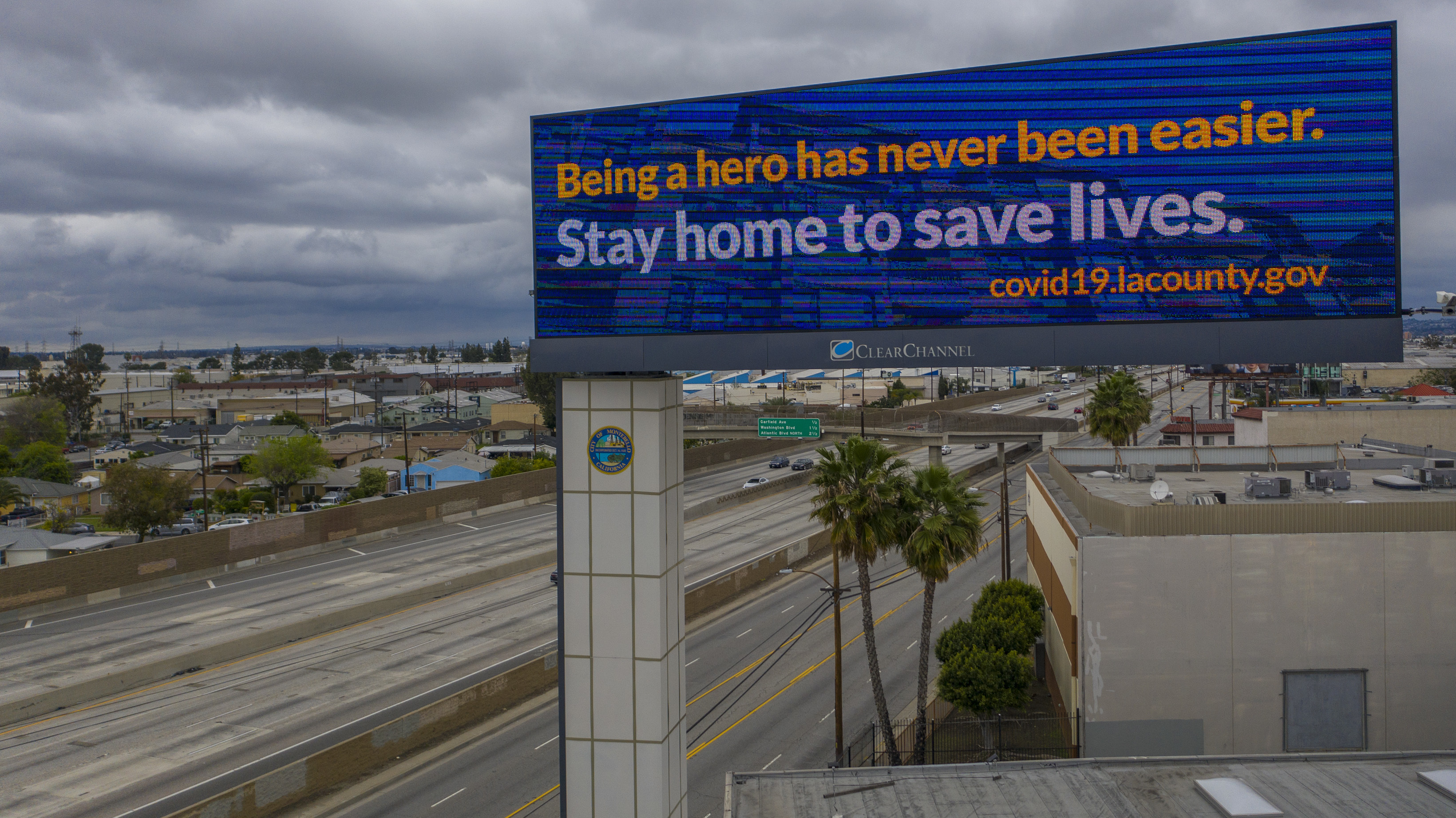 California Gov. Gavin Newsom and his fellow leaders in Oregon and Washington will coordinate their lifting of COVID-19 shutdowns, in a move mirrored by New York and neighboring states in the East. Here, a sign tells people to stay home along the Interstate 5 freeway in Commerce, Calif.