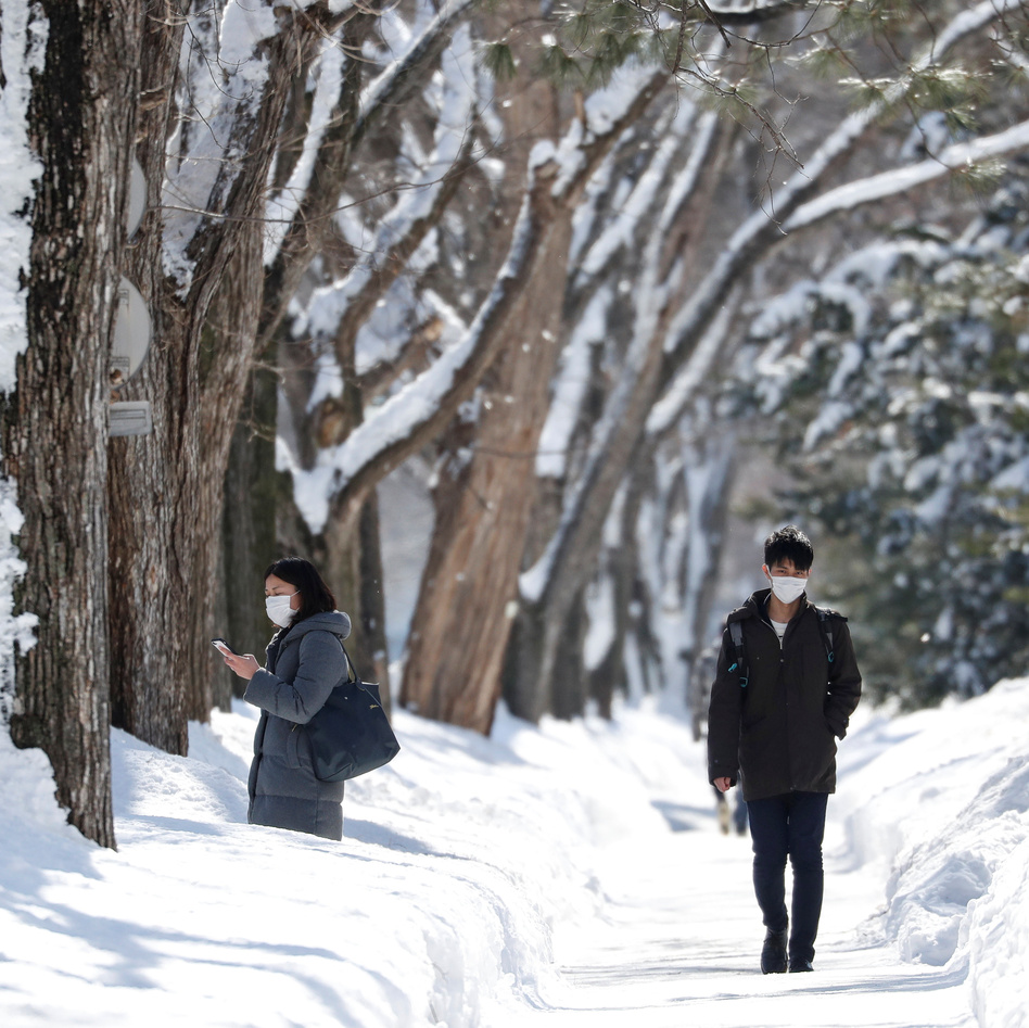 Passersby wearing protective masks walk on a snow-covered street in Sapporo, Hokkaido, Japan, in late February during the first wave of the novel coronavirus. Now, officials have declared a new state of emergency as cases in Hokkaido spike. (Issei Kato/Reuters)