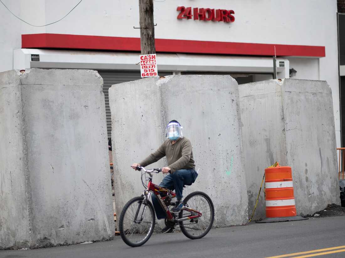 A man wearing a mask pedals his bike in the Corona neighborhood of Queens on April 14, 2020 in New York City. - New York will start making tens of thousands of coronavirus test kits a week, its mayor announced Tuesday, as the city looks to boost testing capacity with a view to ending its shutdown. (Photo by Johannes EISELE / AFP) (Photo by JOHANNES EISELE/AFP via Getty Images)