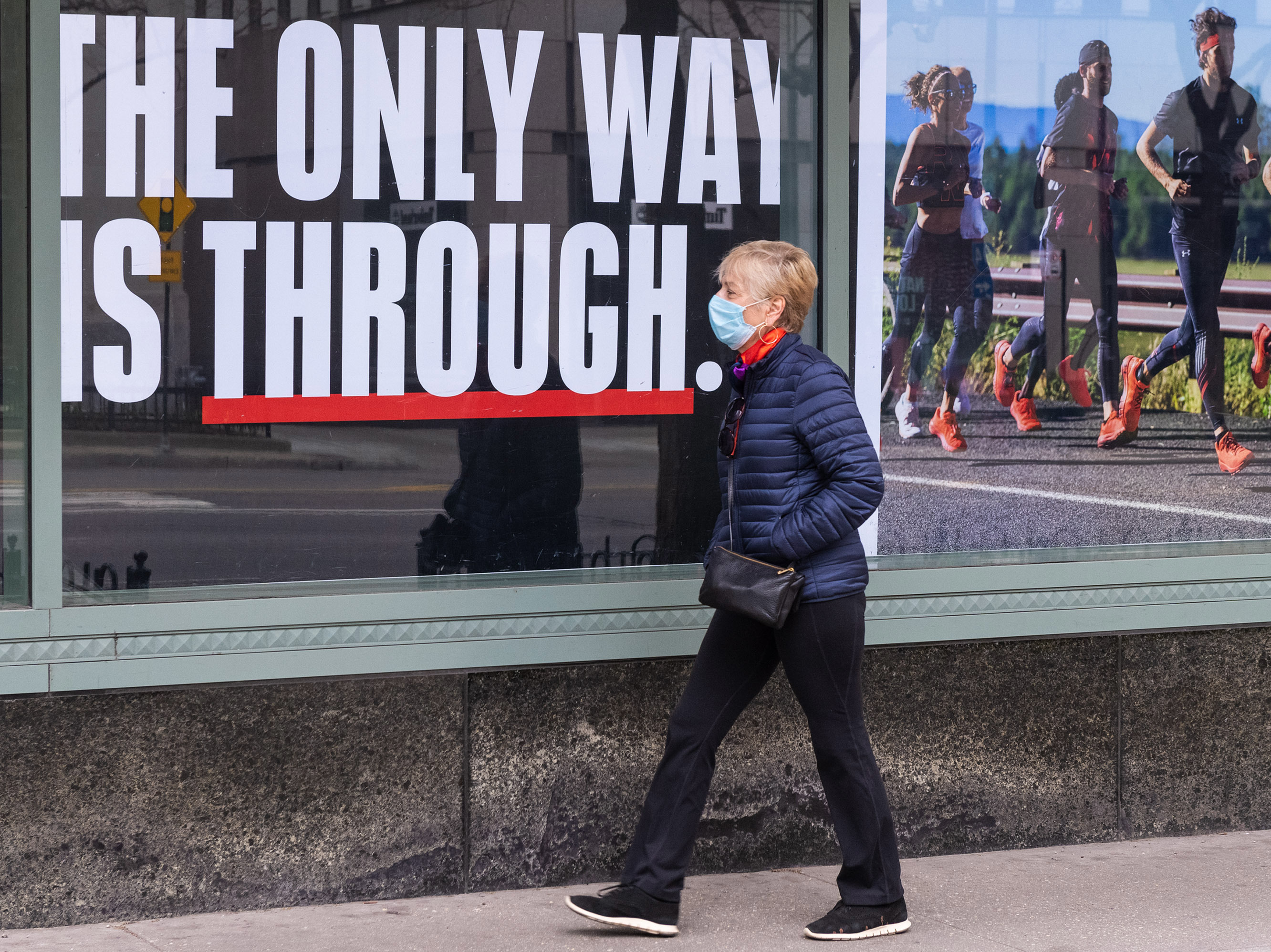 A person wearing a face mask walks down a mostly empty Michigan Avenue in Chicago Thursday. In all major political groups, most people say they support shelter-in-place orders to fight the COVID-19 pandemic, according to a recent poll. (Getty Images)
