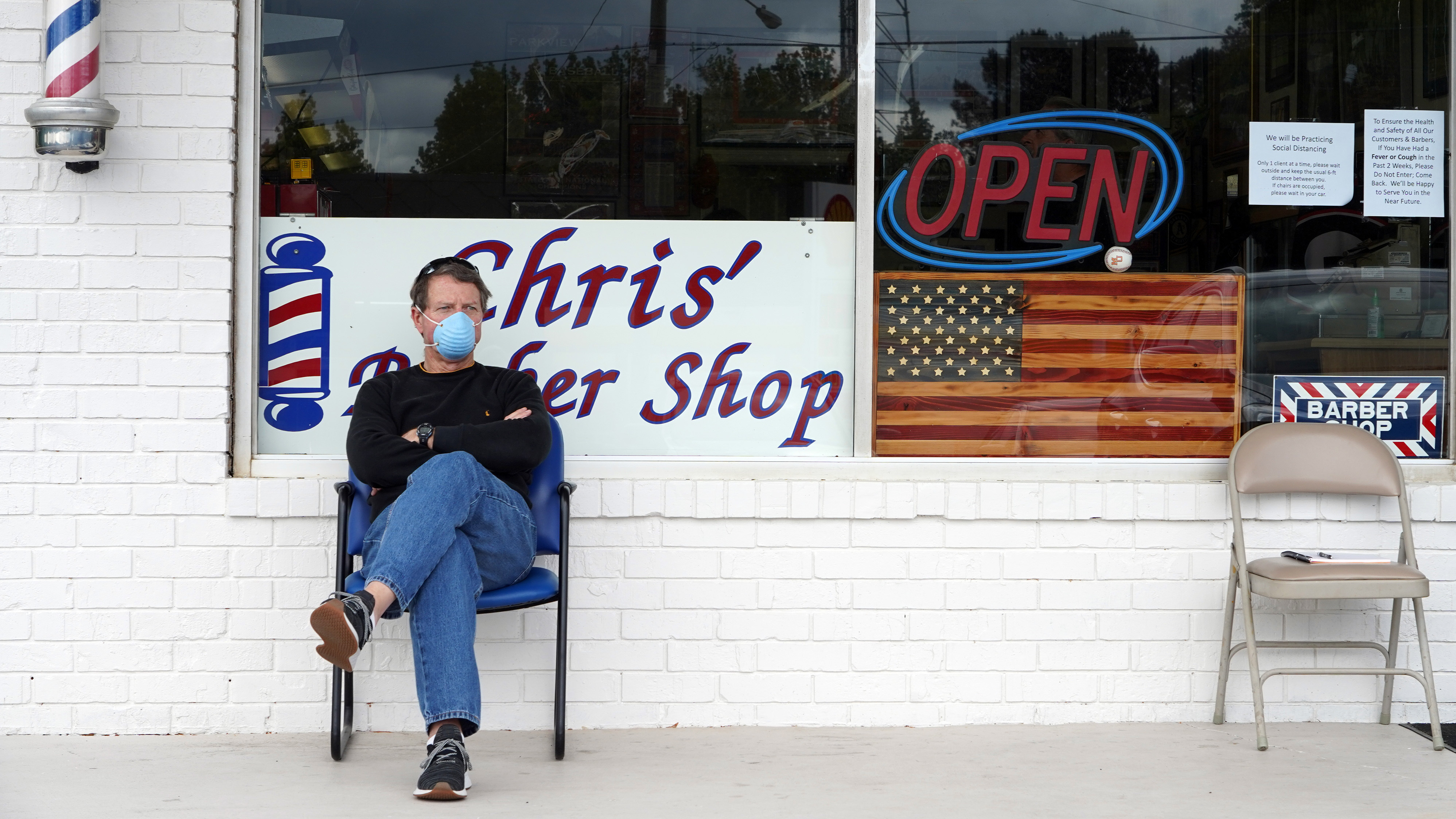 Dan Settle sits outside Chris' Barber Shop as he waits his turn for a haircut in Lilburn, Ga., on Friday. (AFP via Getty Images)