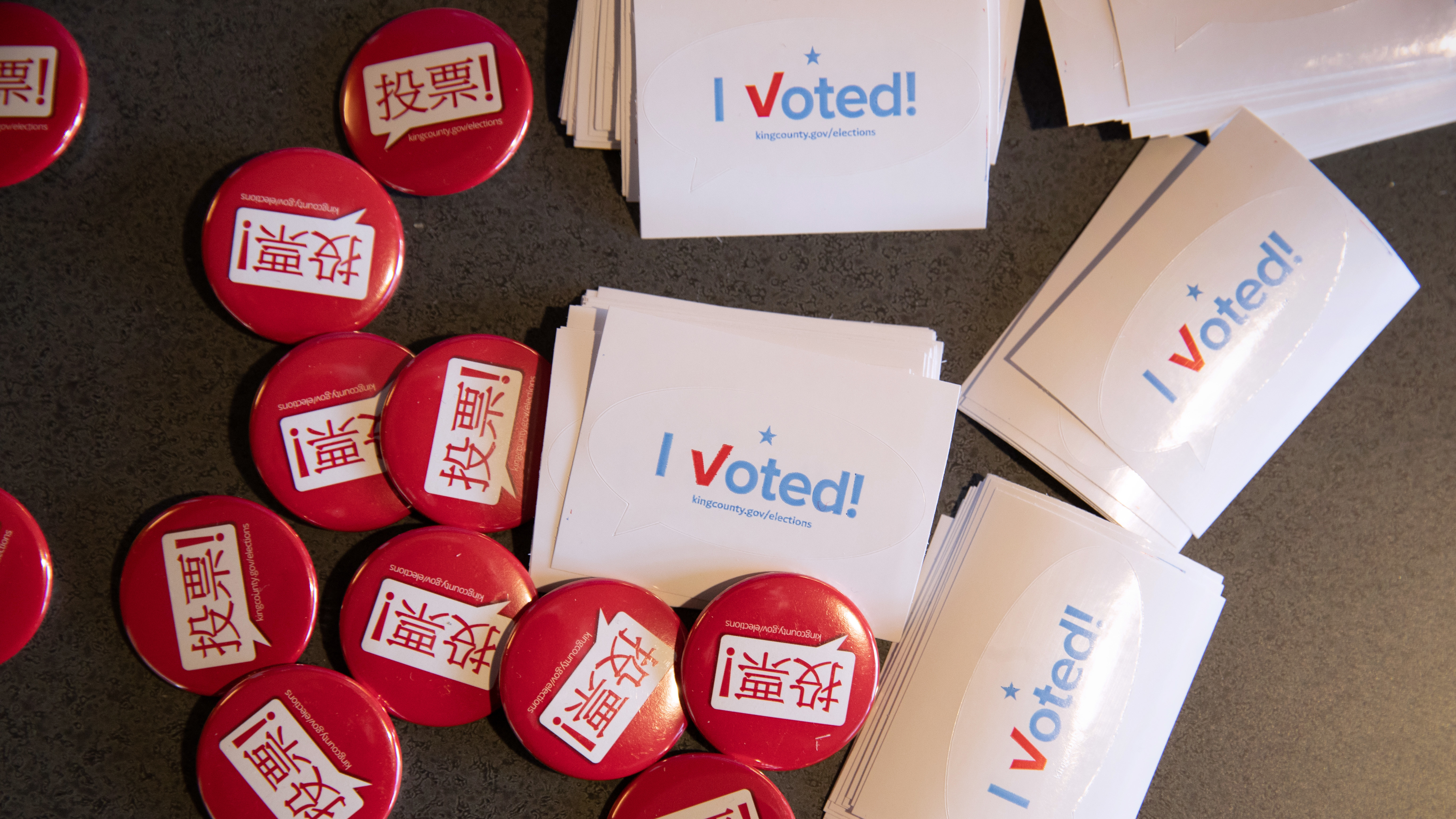 Voting pins and stickers lie next to a ballot box earlier this year during early voting at the King County Elections processing center in Washington. (Getty Images)