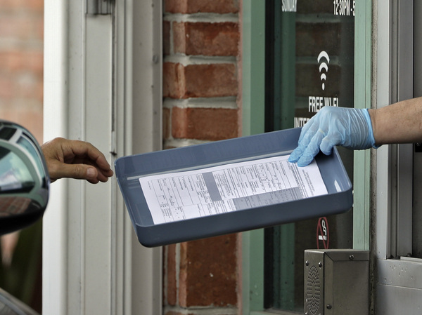 A Hillsborough County Library employee hands unemployment paperwork to residents in Tampa, Fla.