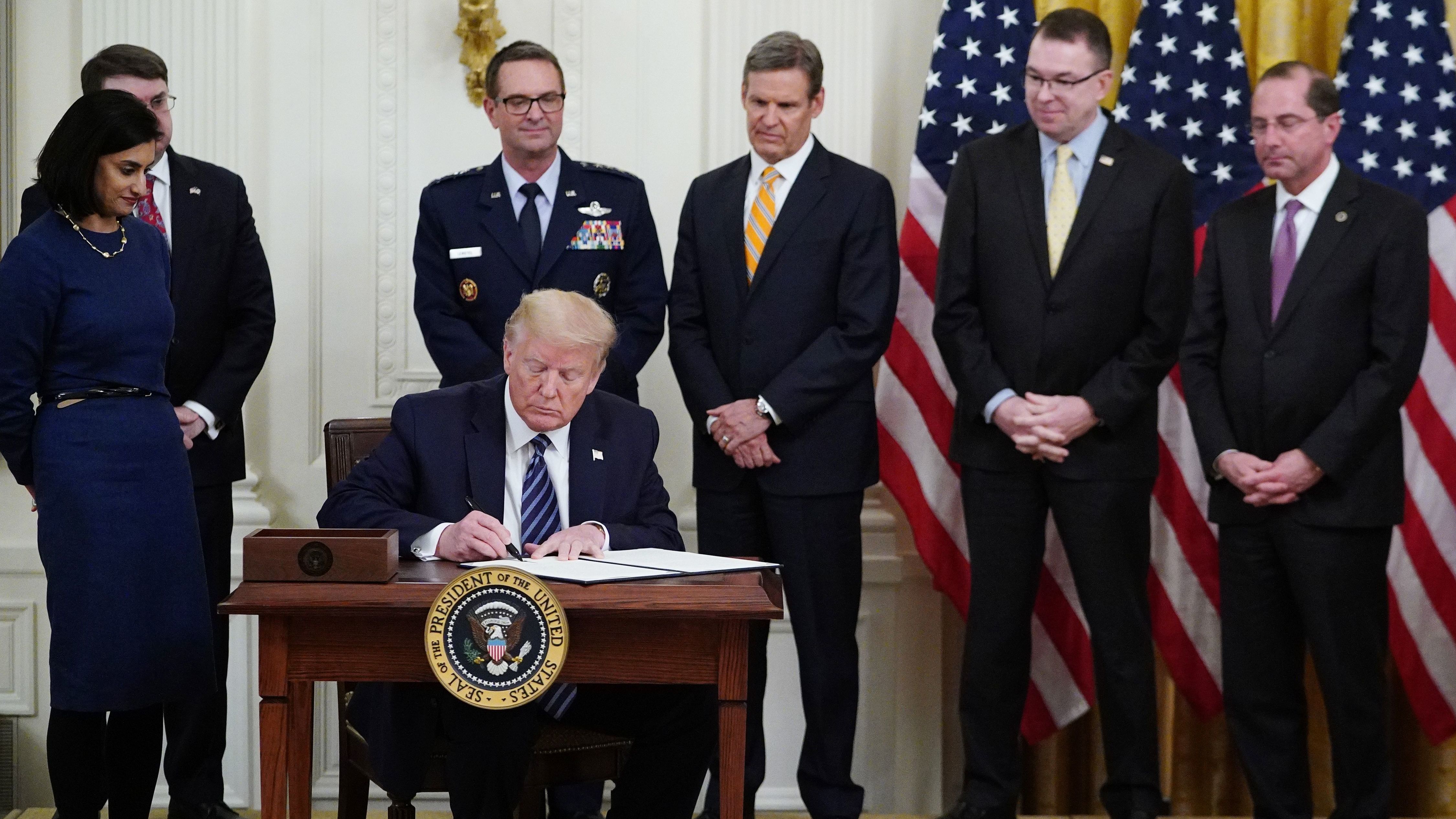 President Trump, surrounded by federal officials on Thursday, signs a proclamation for Older Americans Month during an event on protecting seniors from the coronavirus. (AFP via Getty Images)