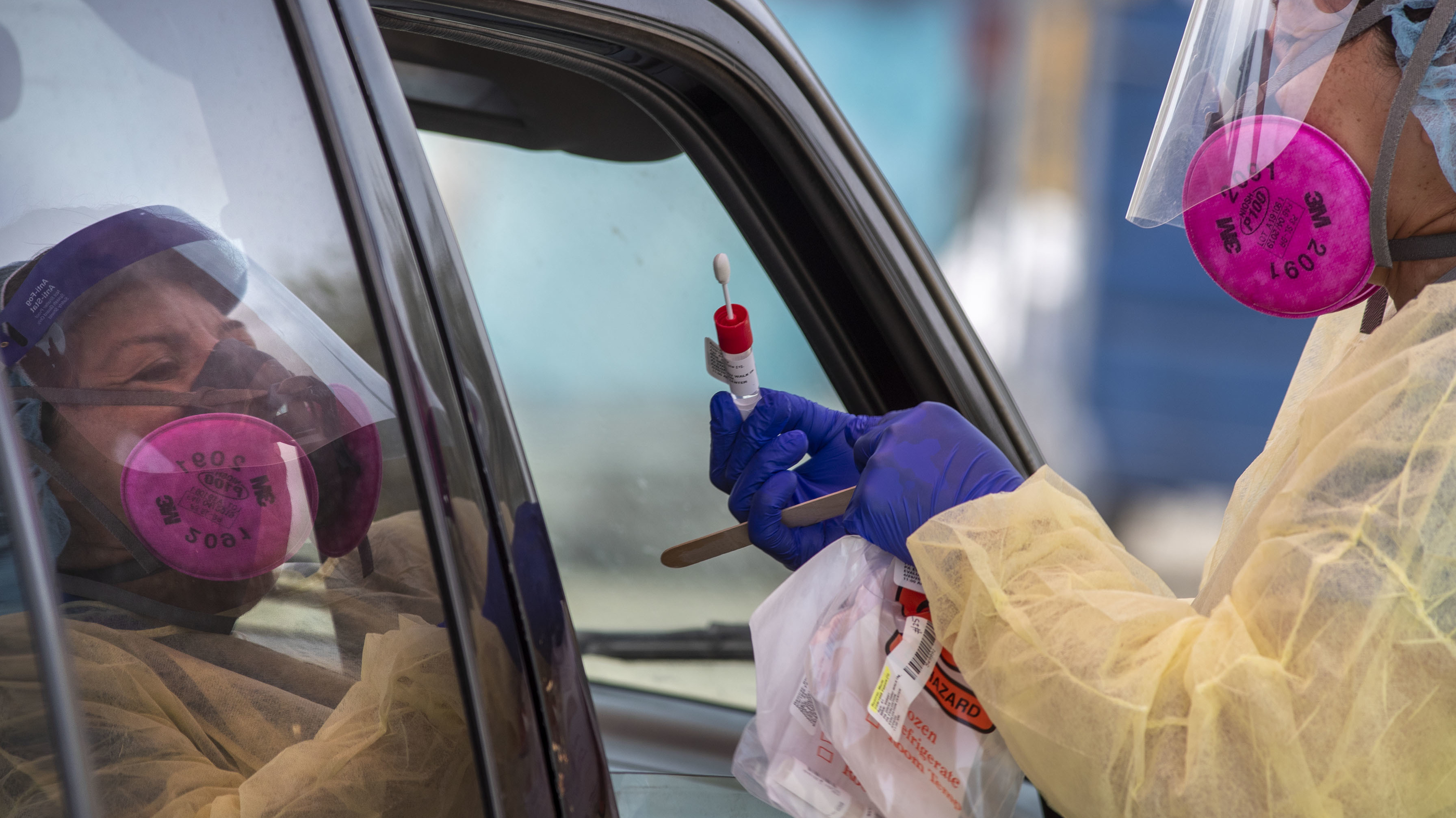 A member of the AltaMed Health Services staff prepares to take a sample at a drive-through coronavirus testing site in Los Angeles.