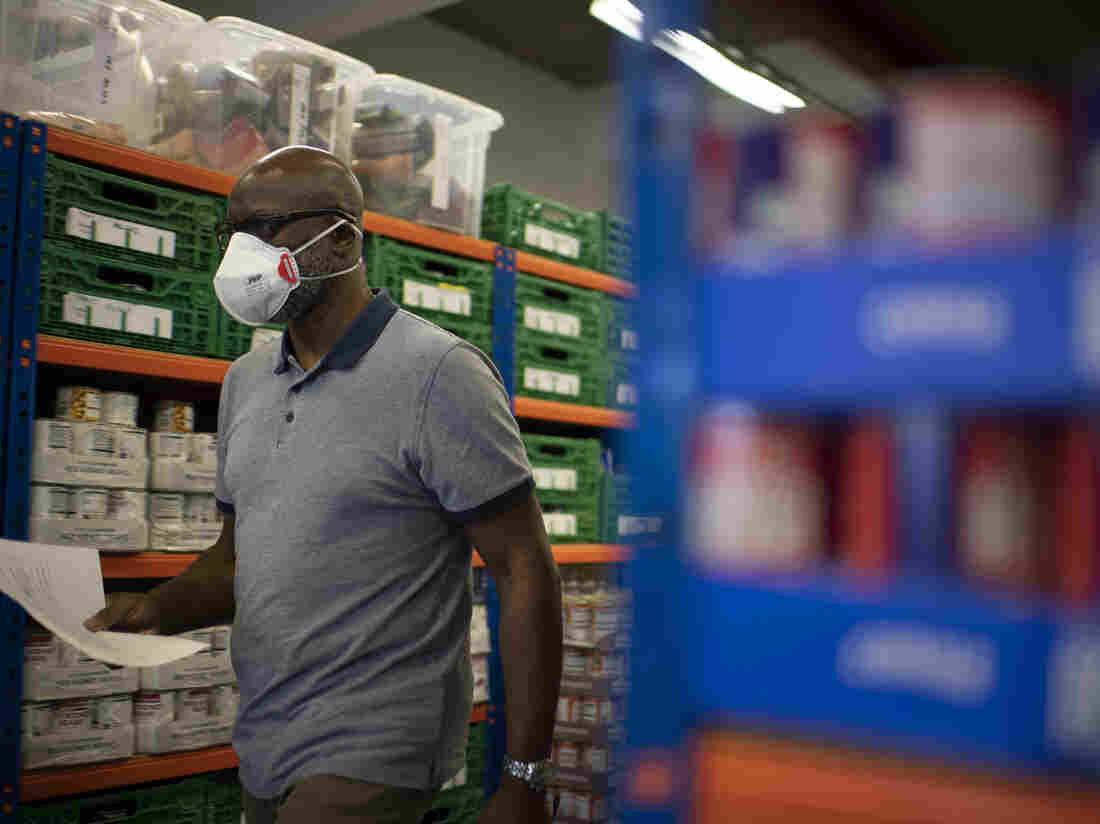 Co-founder and Chair of the First Love foundation foodbank, Aerold Bentley walks past goods for distribution to families, at the First Love foundation foodbank warehouse in Tower Hamlets in east London on April 24, 2020, (Photo by DANIEL LEAL-OLIVAS/AFP via Getty Images)