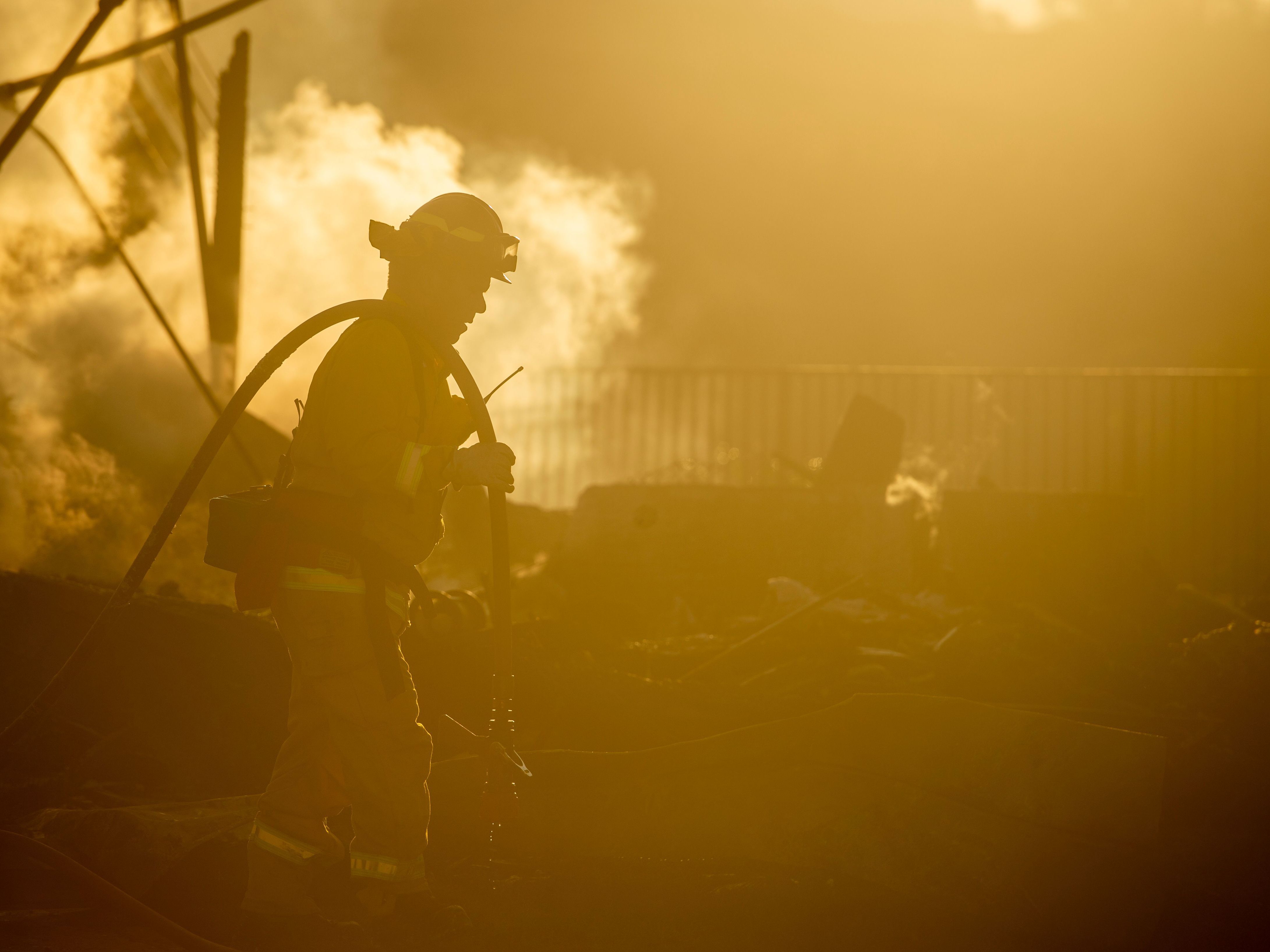 A firefighter sprays down the smoldering remains of a burning home during the Hillside Fire in the North Park neighborhood of San Bernardino, Calif., on Oct. 31, 2019. Some wildland firefighters worry whether they can do their jobs safely during a global pandemic. (AFP via Getty Images)