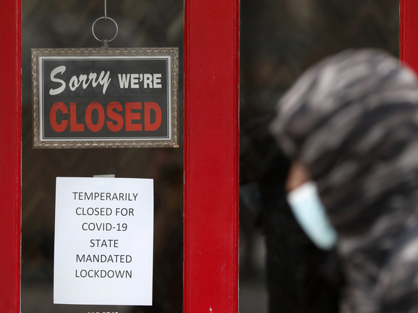 A pedestrian walks by a closed shop in Grosse Pointe, Mich., on Thursday. The Labor Department is expected to report on Friday that the U.S. lost millions of jobs last month because of the coronavirus pandemic.