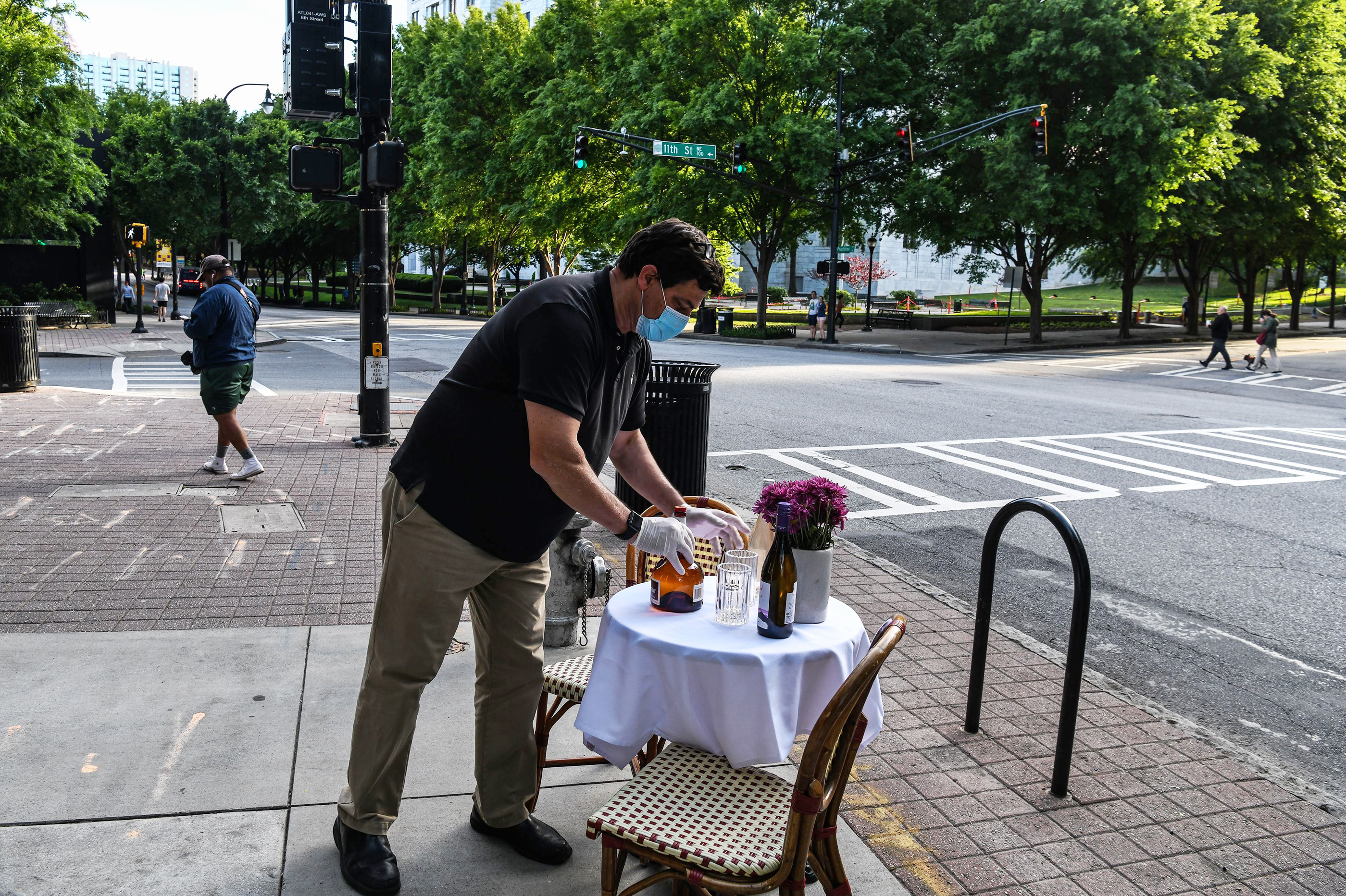 A man decorates a bistro table outside his restaurant amid the coronavirus pandemic in Atlanta on April 27. As states reopen, some are allowing restaurants to add outdoor seating in streets and parking lots. (AFP via Getty Images)