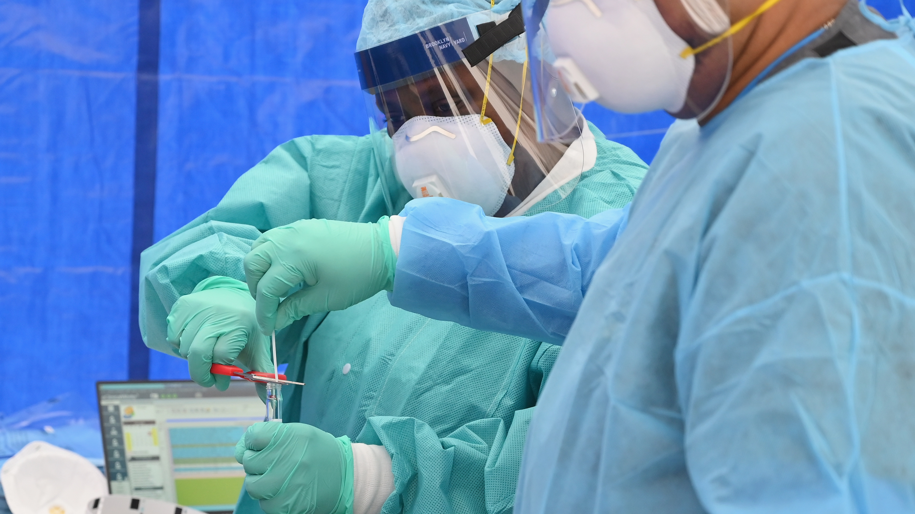 Health care workers place a nasal swab from a patient into a tube for testing at a free pop-up coronavirus testing site in Brooklyn.