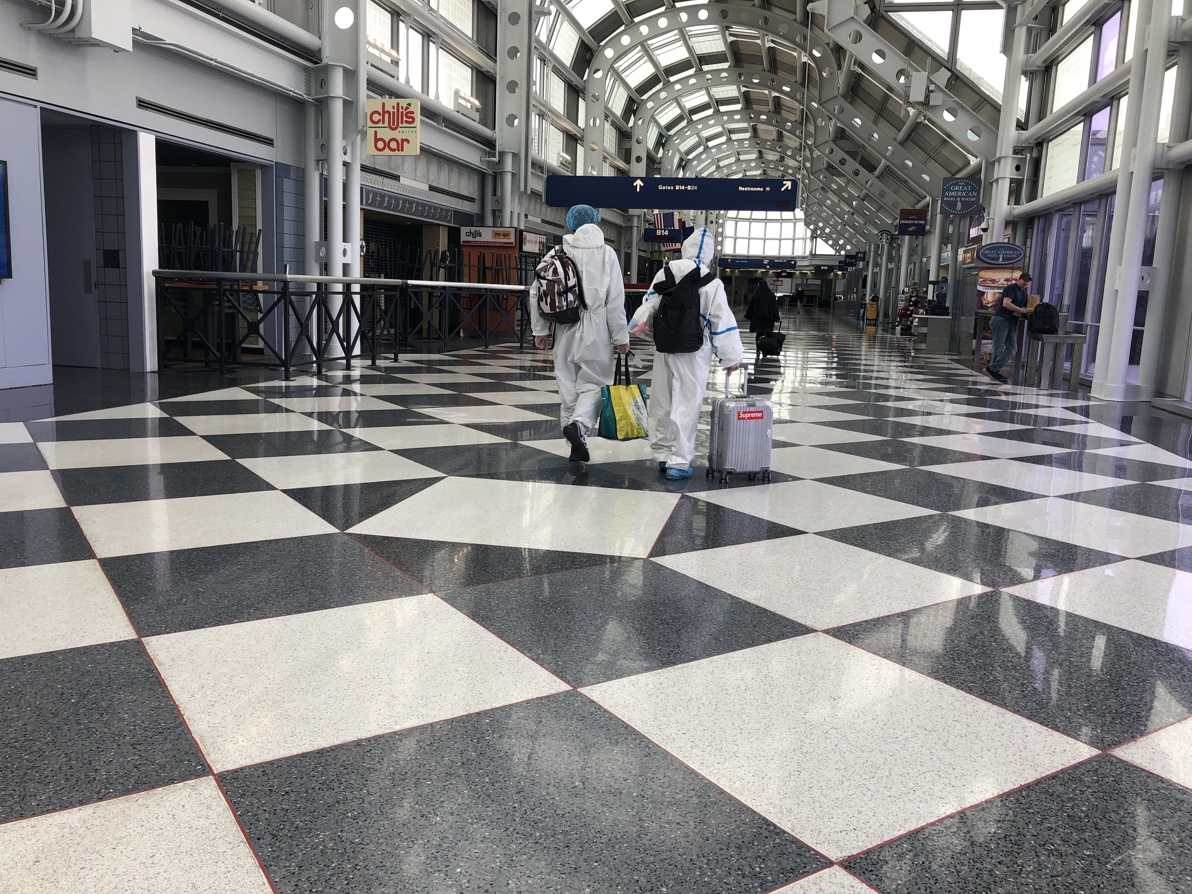 A couple dressed in protective gear walks through Chicago's O'Hare International Airport last week as the normal frantic bustle in the terminal was replaced by an unsettling calm. (NPR)